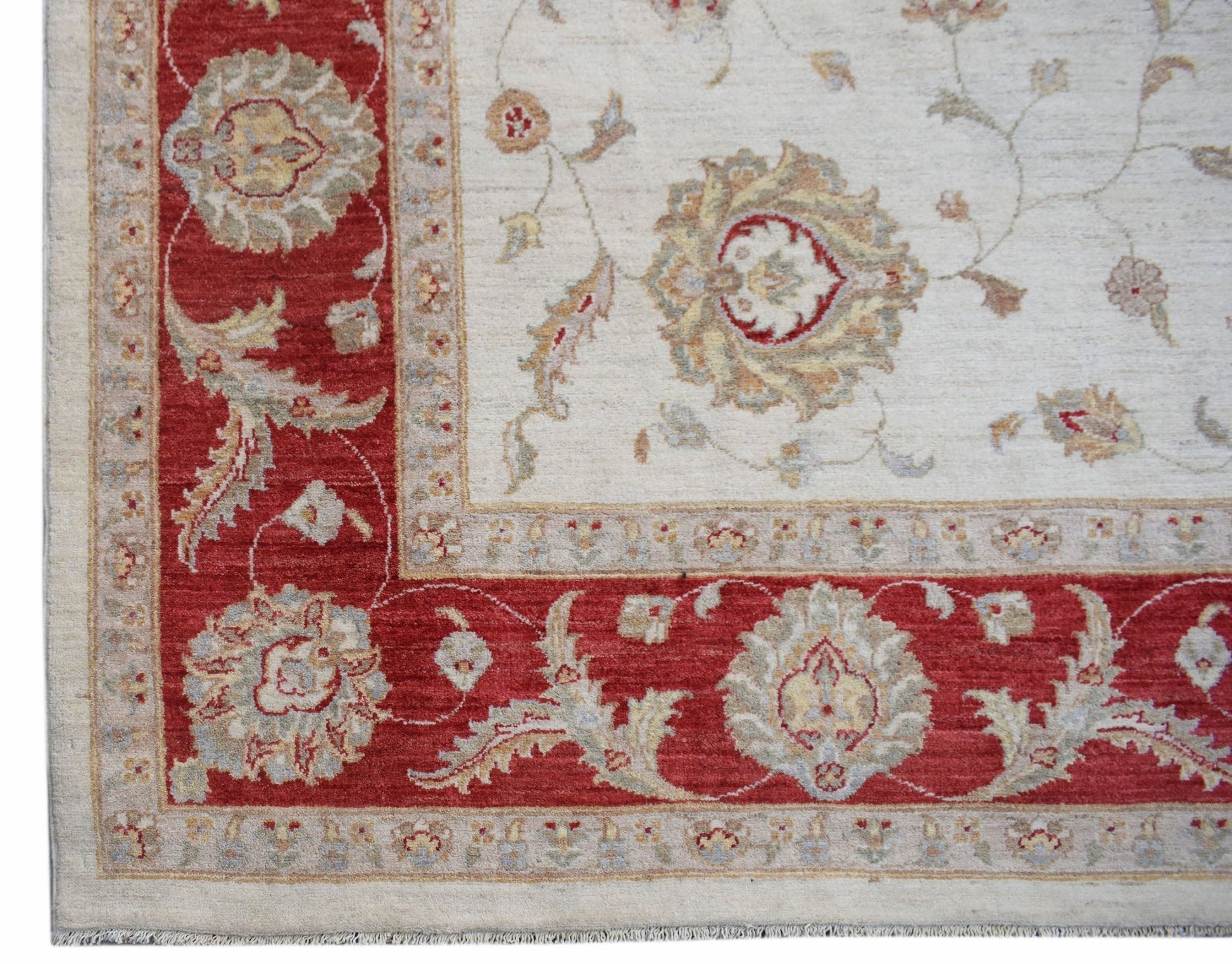 A handmade Afghan Chobi rug featuring a cream field with floral motifs and a red border.