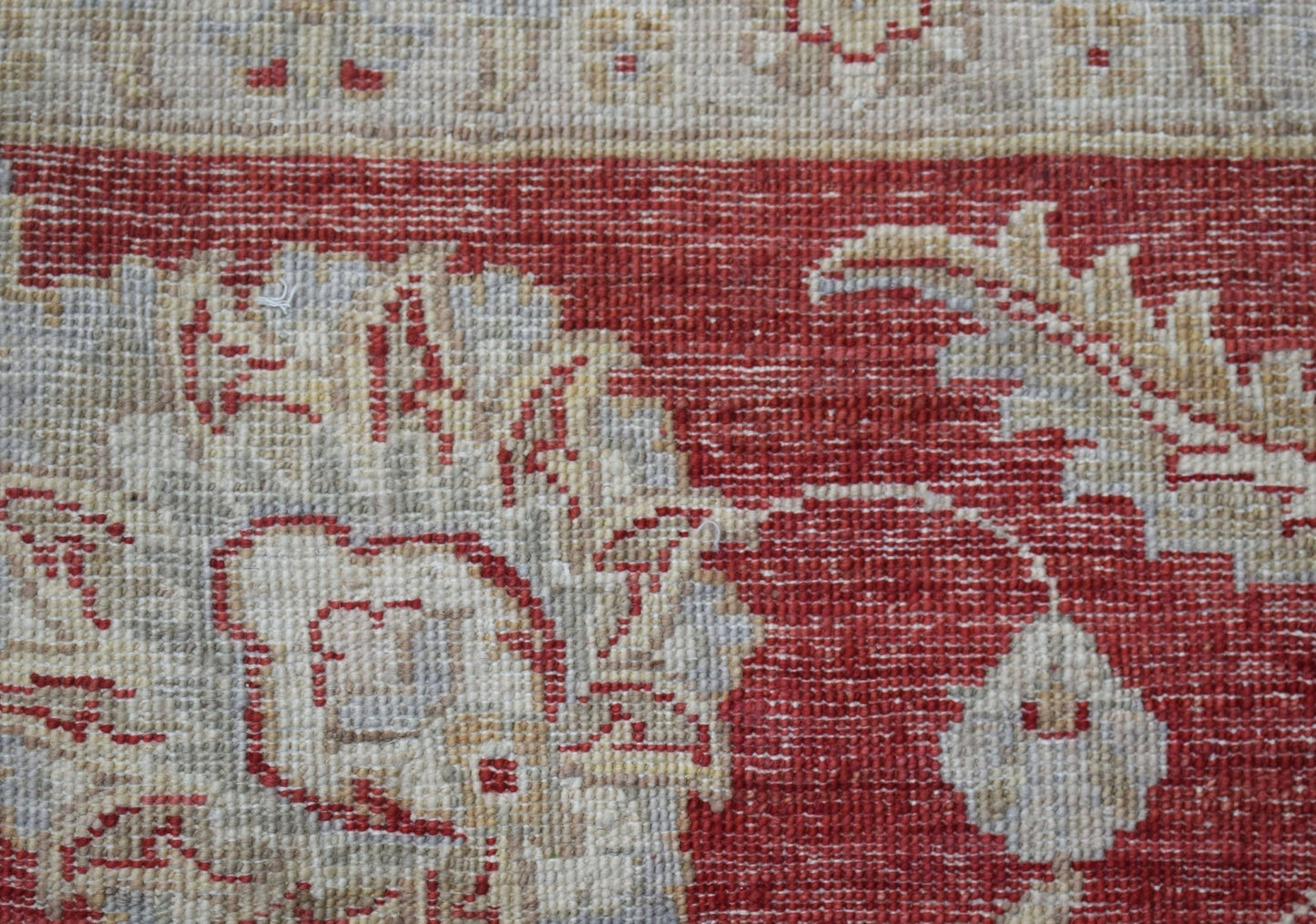 A close-up of a handwoven Afghan Chobi rug featuring intricate floral patterns in red and beige.