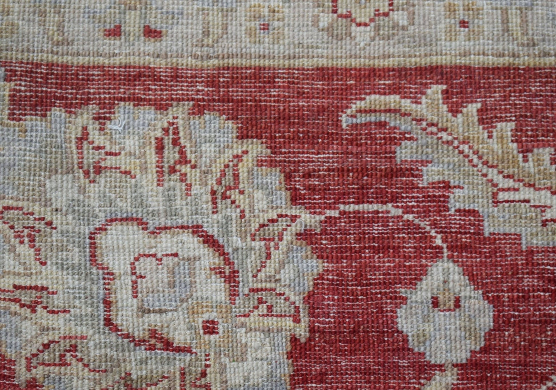 A close-up of a handwoven Afghan Chobi rug featuring intricate floral patterns in red and beige.