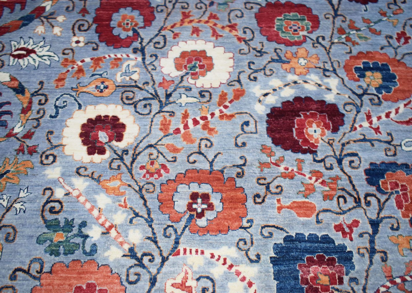 An Afghan Chobi rug featuring a traditional floral pattern in red, orange, and blue on a blue base.