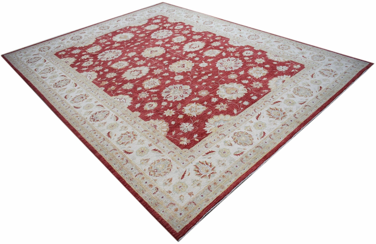 An Afghan Chobi rug featuring a red field with intricate floral patterns and a cream border.