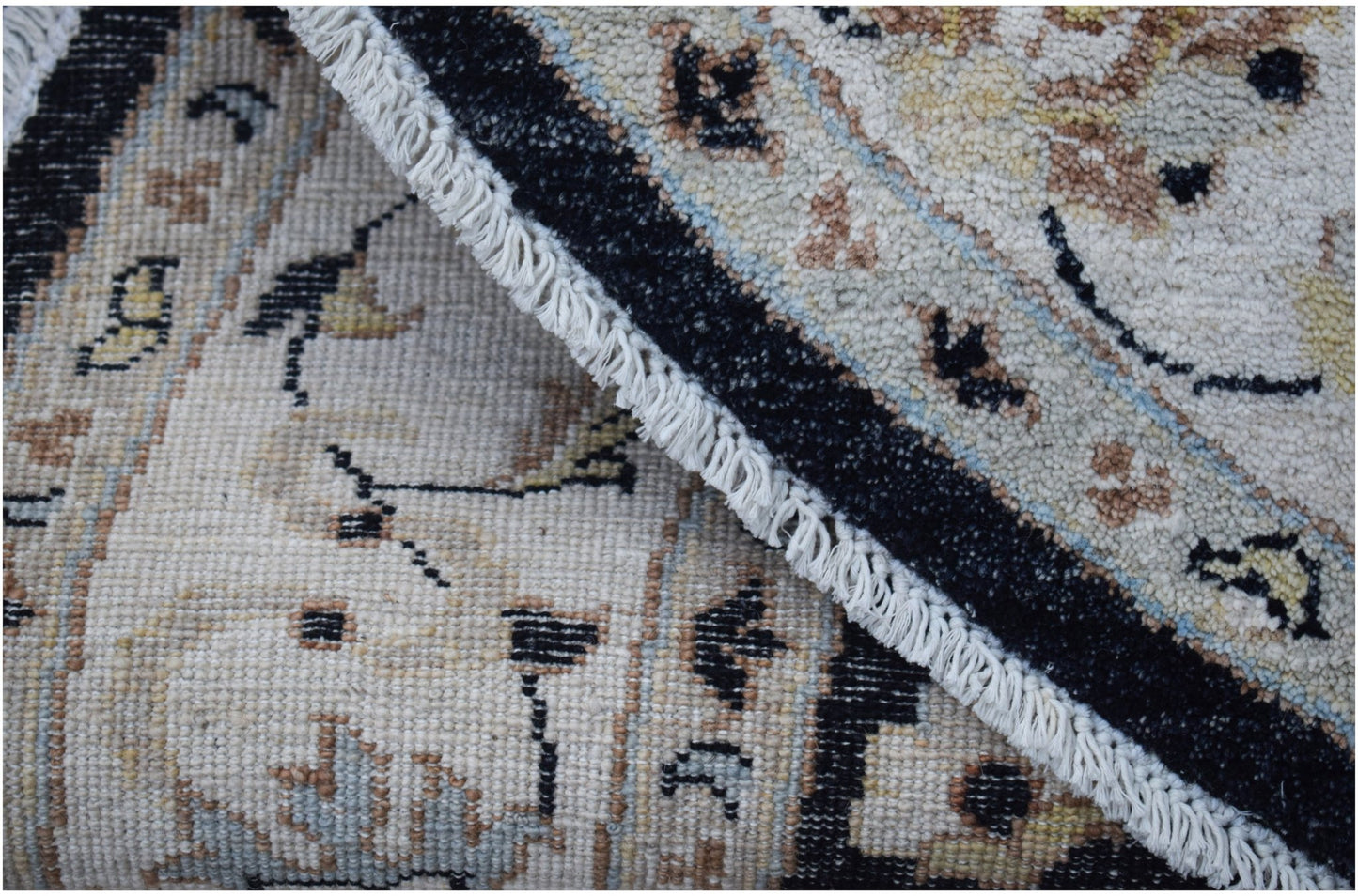 A folded Afghan Chobi rug featuring a traditional floral pattern in neutral and black tones.