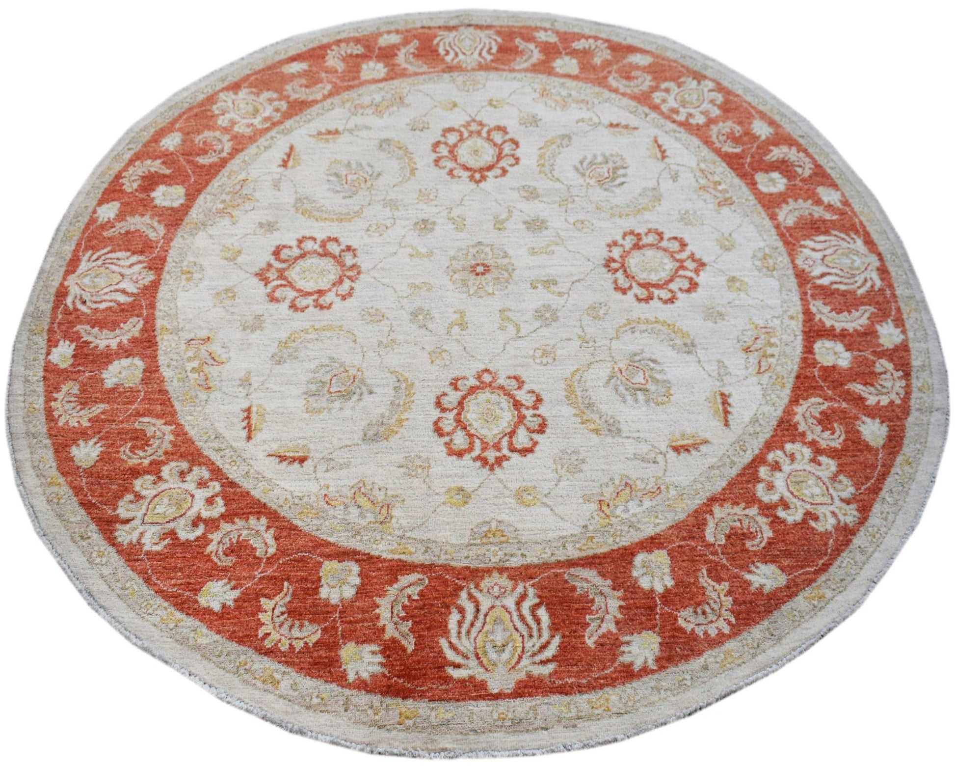 A round Afghan Chobi rug featuring a cream center with orange floral motifs and a wide orange border.