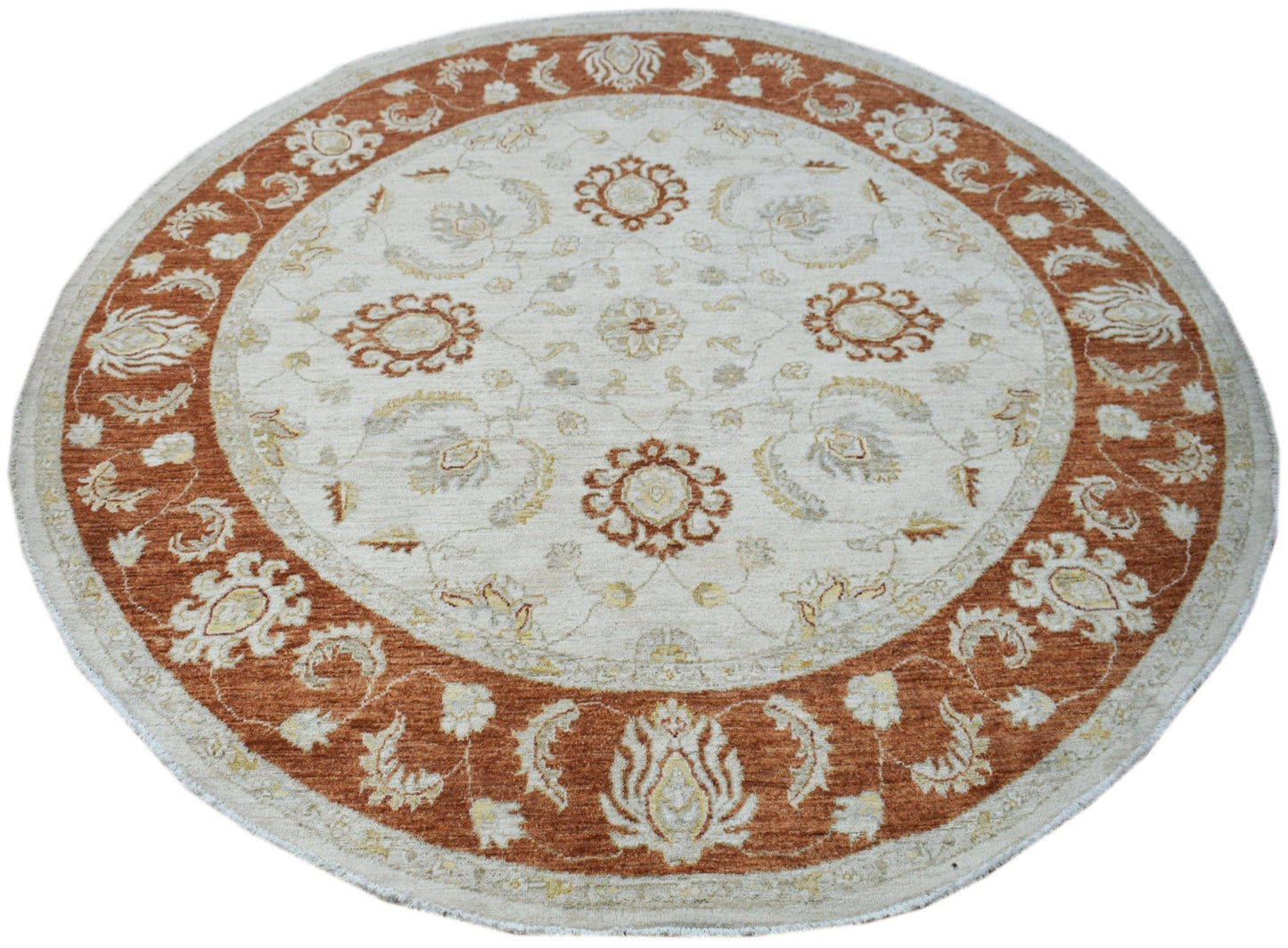 A round Afghan Chobi rug featuring a cream center and a wide, rust-colored floral border.