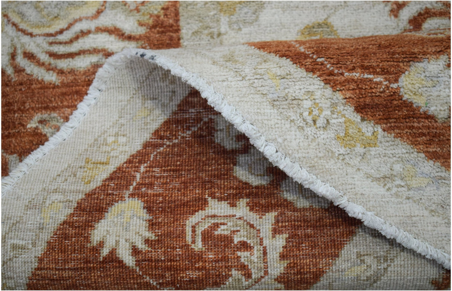 A close-up view of a handwoven Afghan Chobi rug featuring a traditional floral pattern in rust.