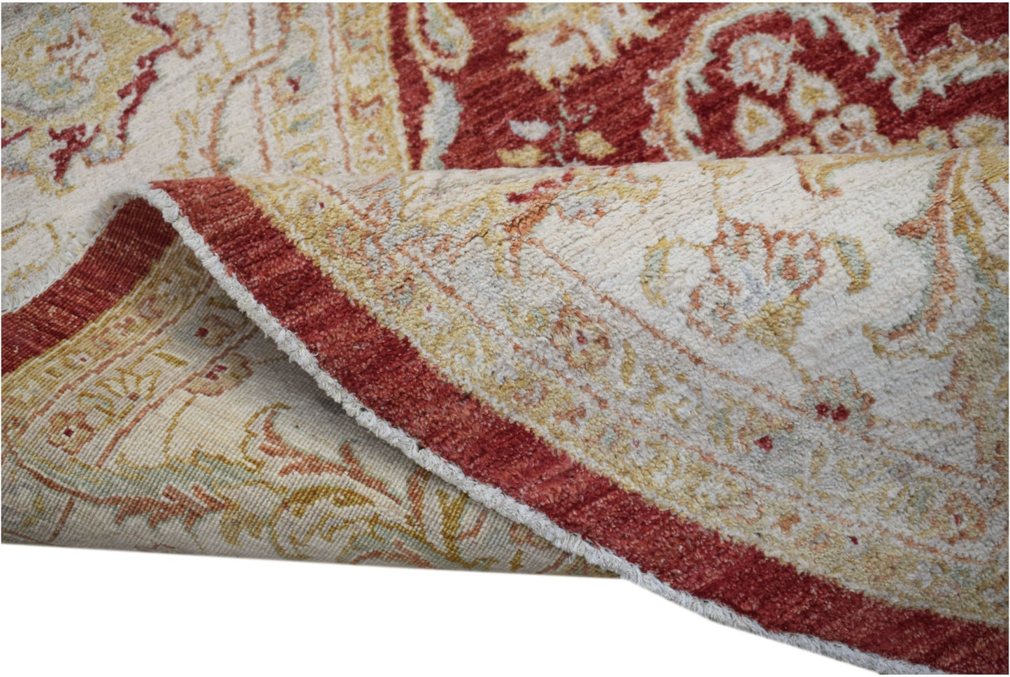 A corner of a handwoven Afghan Chobi rug showing its red and cream floral pattern and wool texture.