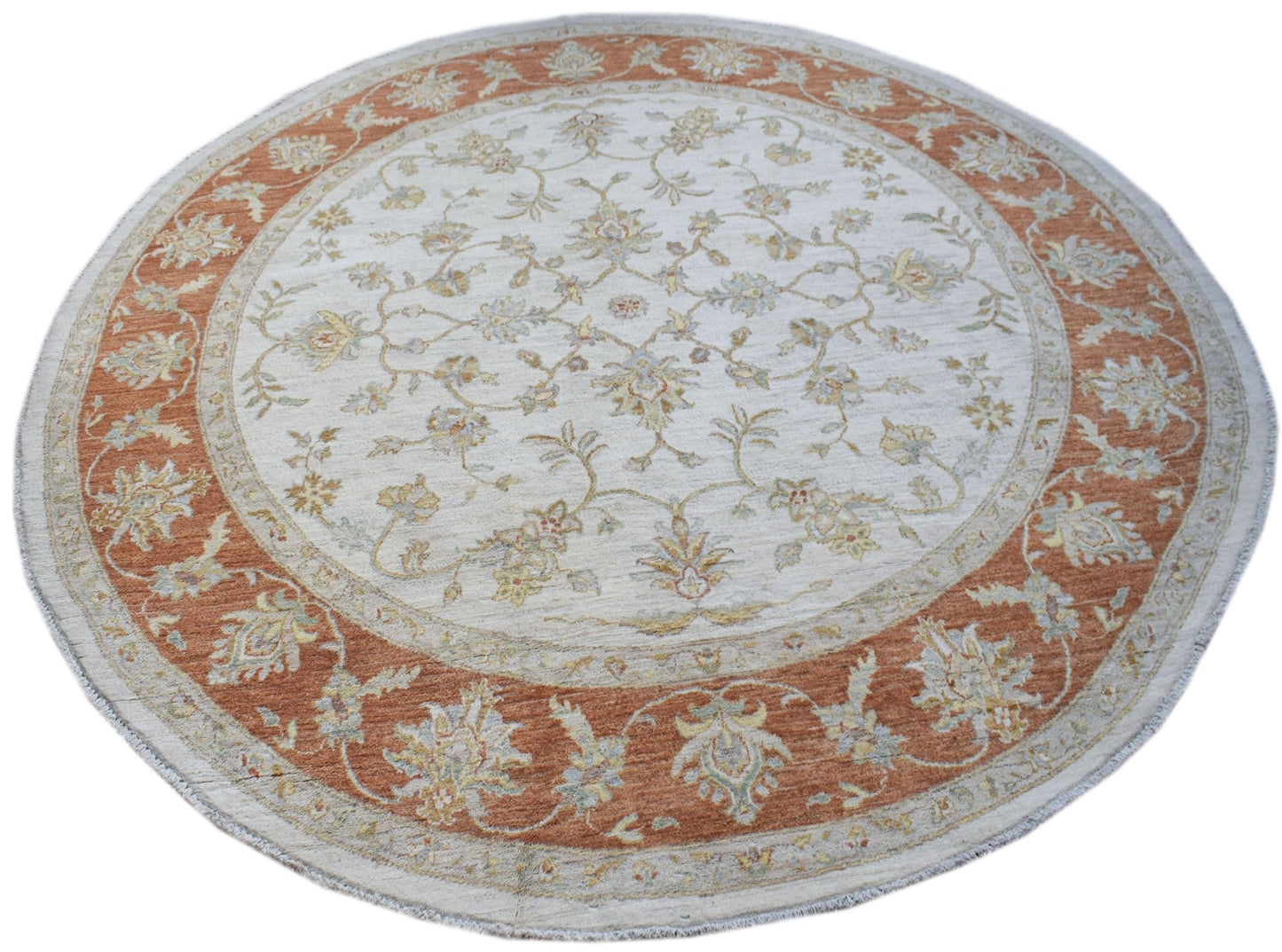 A round Afghan Chobi rug featuring a traditional floral pattern in terracotta and cream tones.