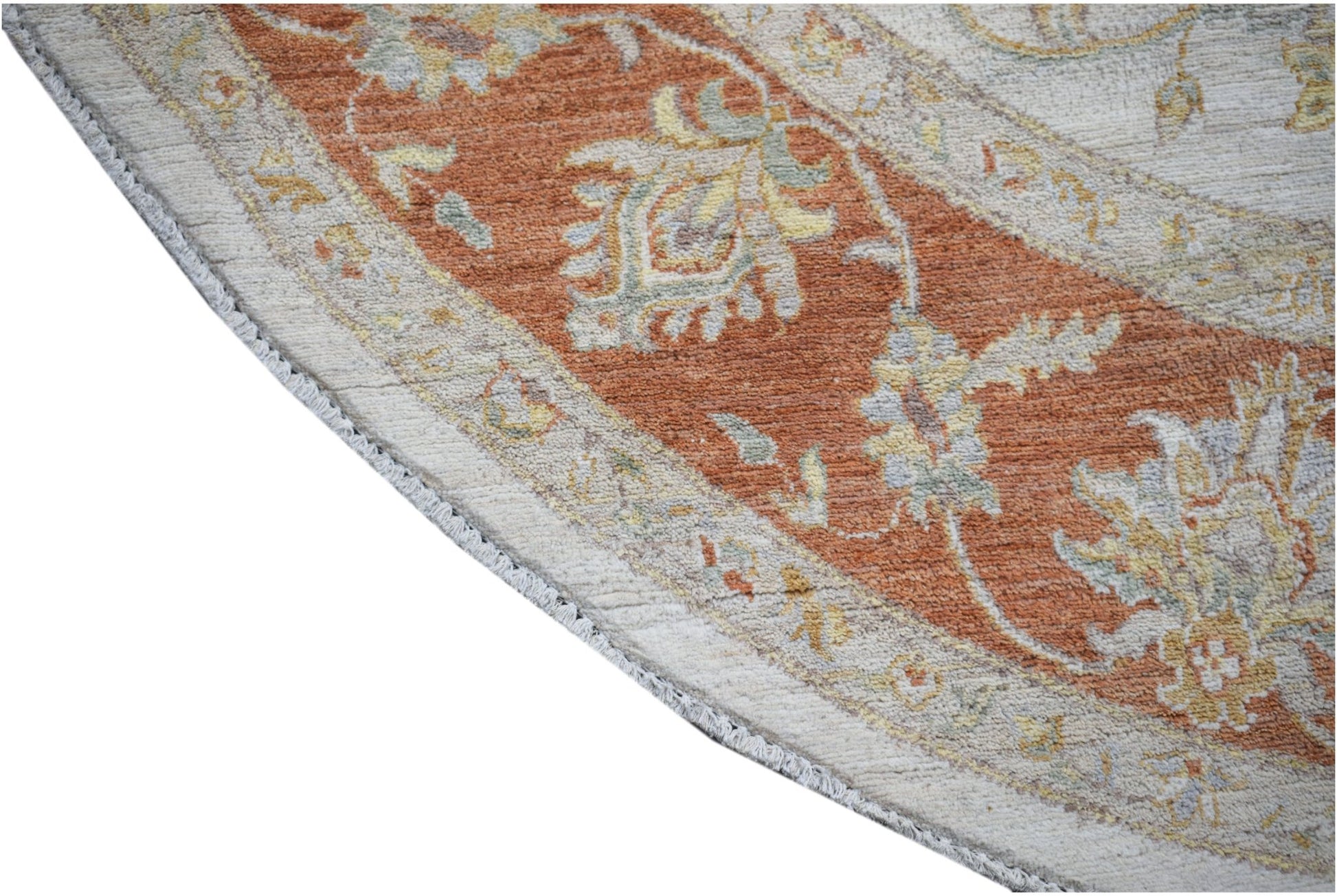 A close-up of a round Afghan Chobi rug featuring a terracotta border with floral patterns.