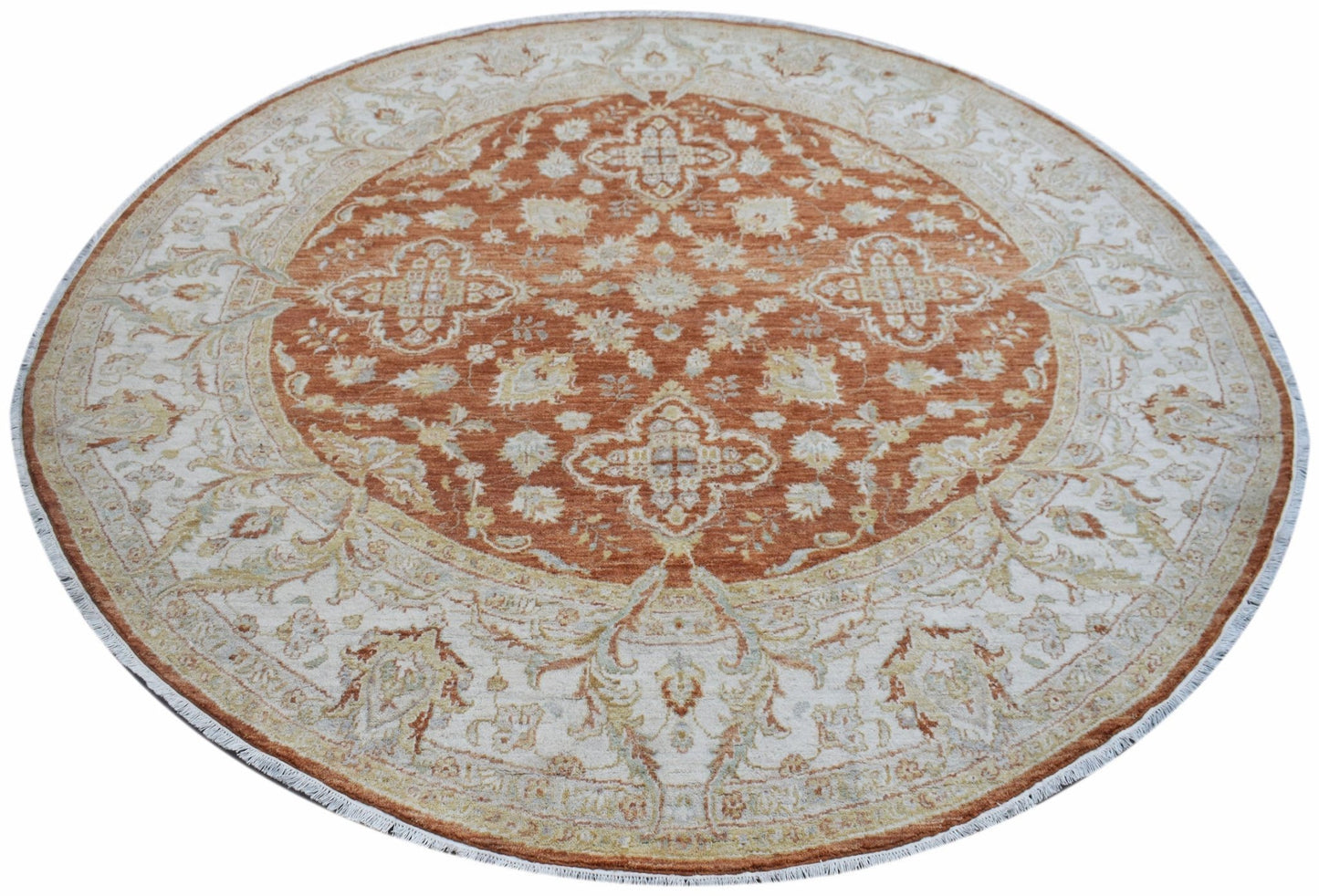 A round Afghan Chobi rug featuring a rust-orange center with intricate floral patterns.