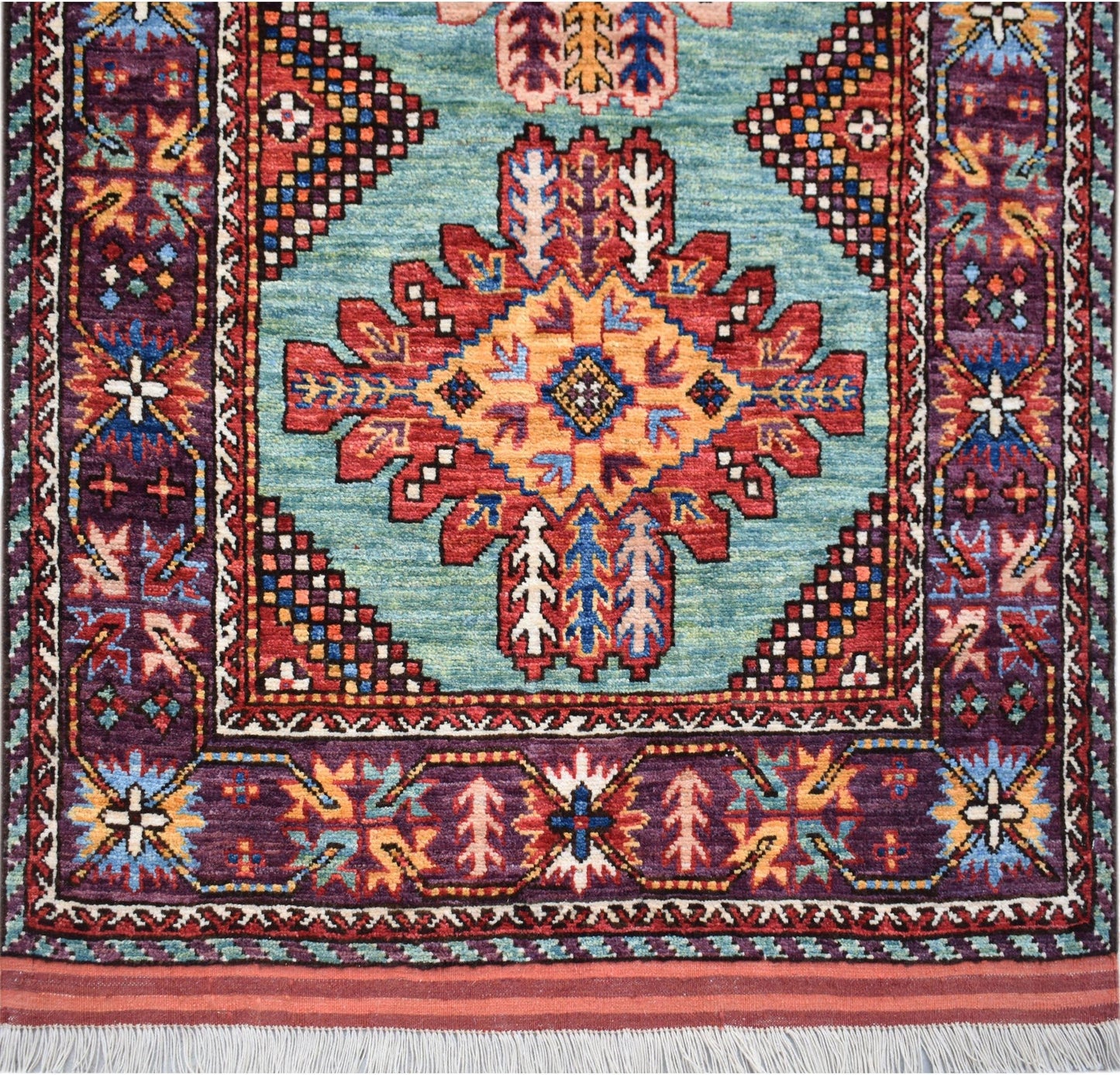 Handwoven Afghan Herati runner featuring a central geometric medallion on a light blue field.