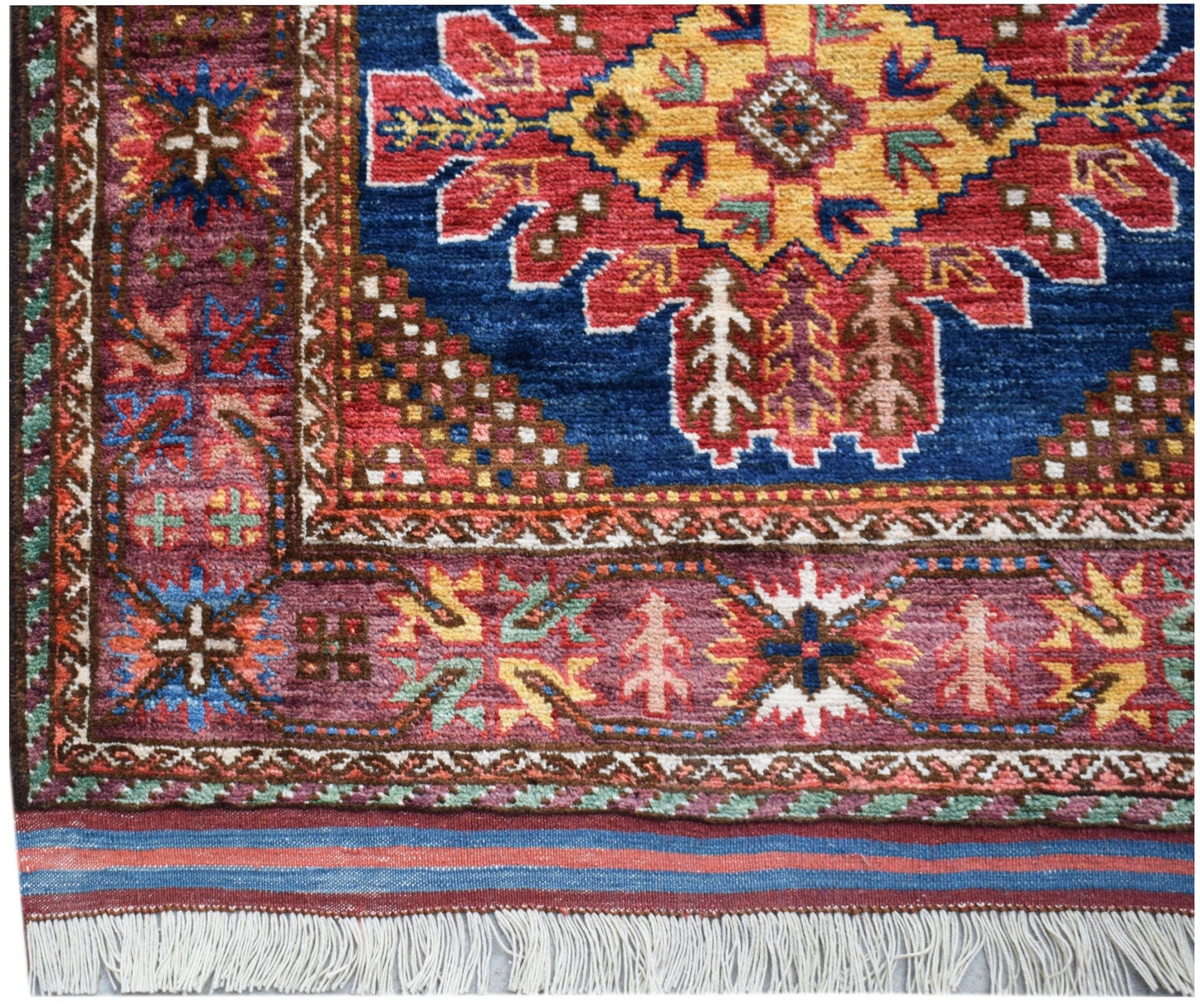 A handwoven Afghan Herati runner featuring a traditional geometric pattern in red, blue, and gold.