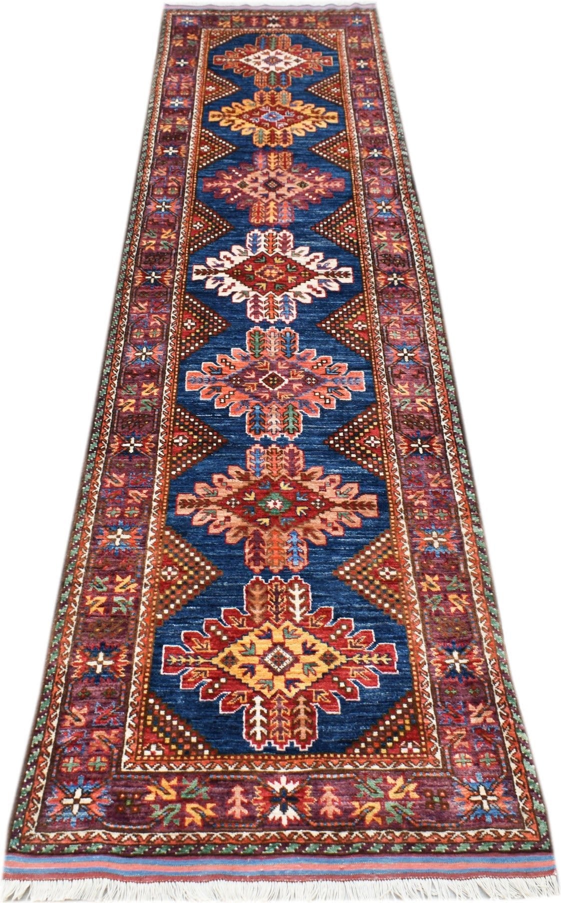 A handmade Afghan Herati runner rug featuring a blue field with repeating geometric medallions.
