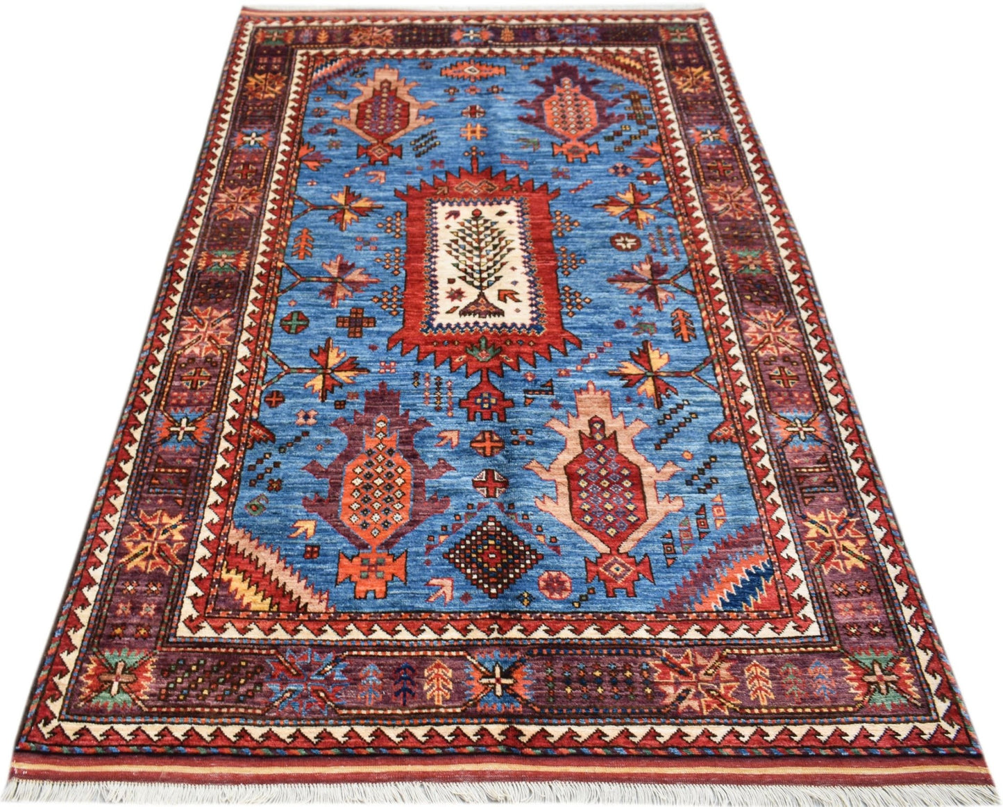 Handwoven Afghan Herati rug featuring a central tree motif on a blue field with geometric borders.