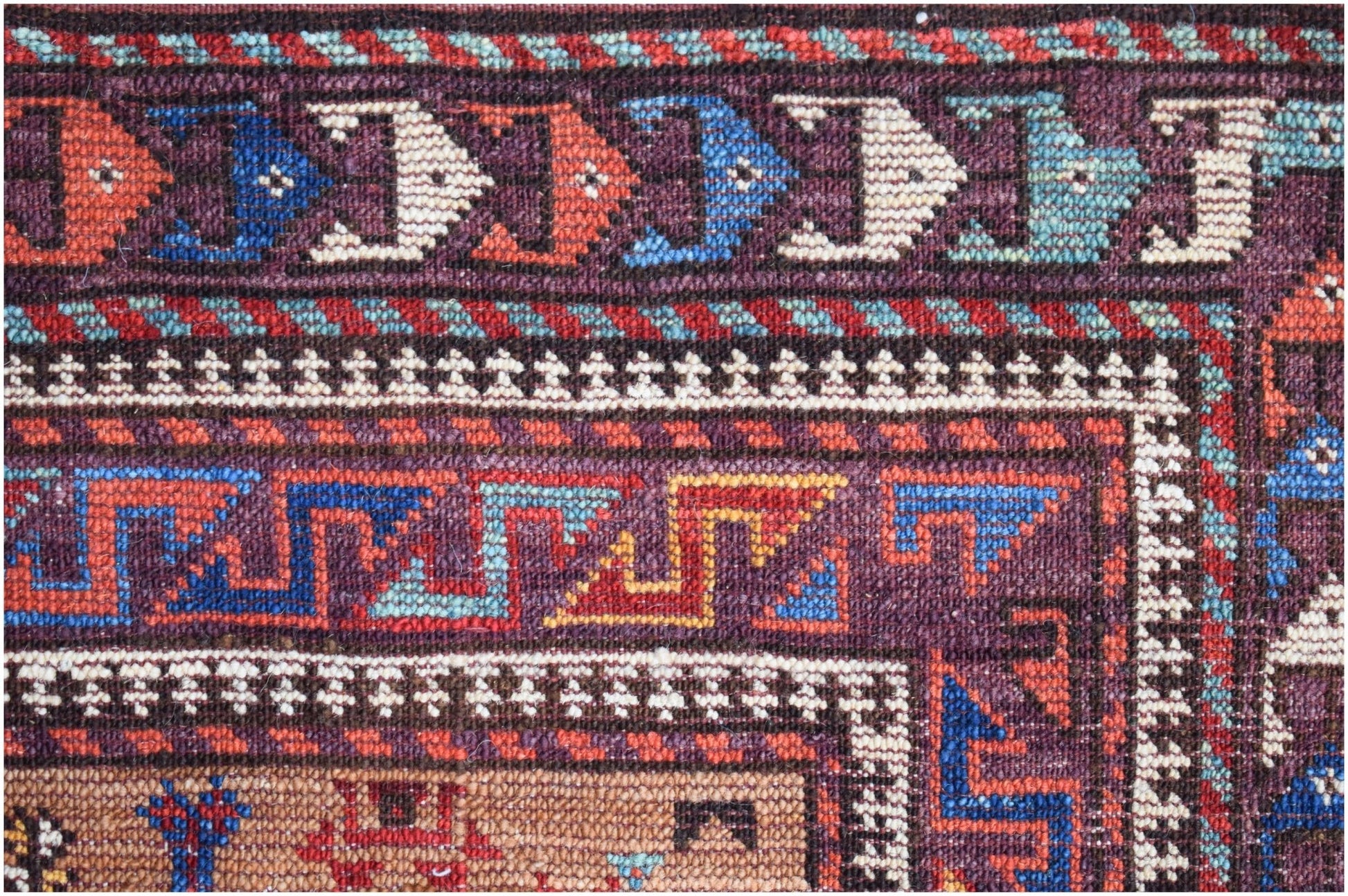 A close-up of an Afghan Herati rug featuring intricate geometric patterns in red, blue, and cream.