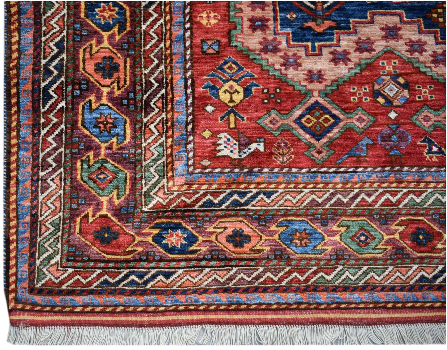 A handmade Afghan Herati rug featuring a red field with geometric patterns and a fringed edge.