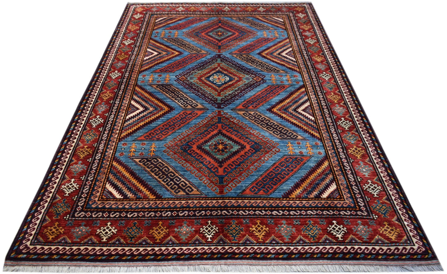 A rectangular Afghan Herati rug featuring a blue field with geometric diamond patterns and red borders.