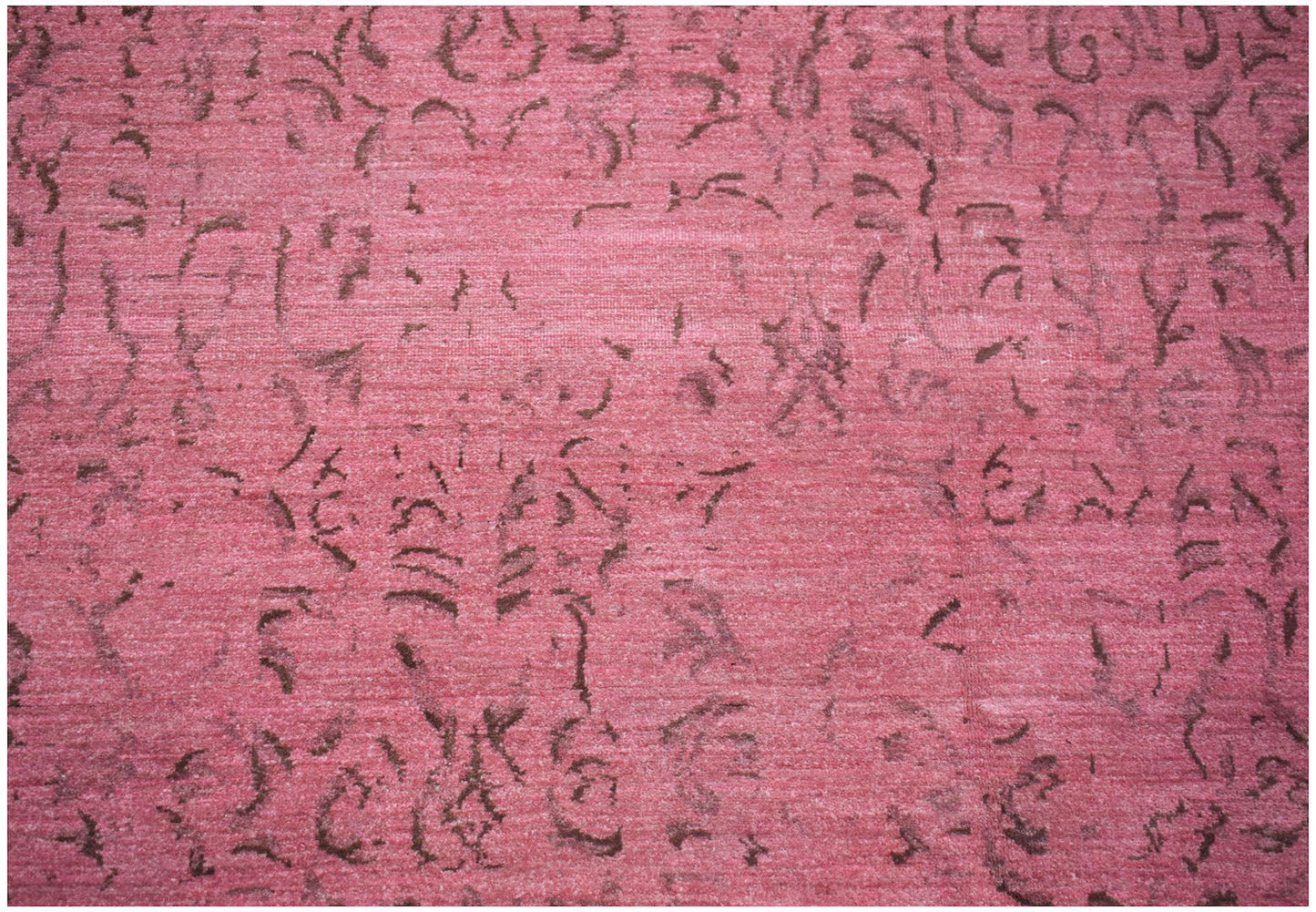 A handmade Afghan Chobi rug featuring a distressed, overdyed pink pattern with dark brown motifs.