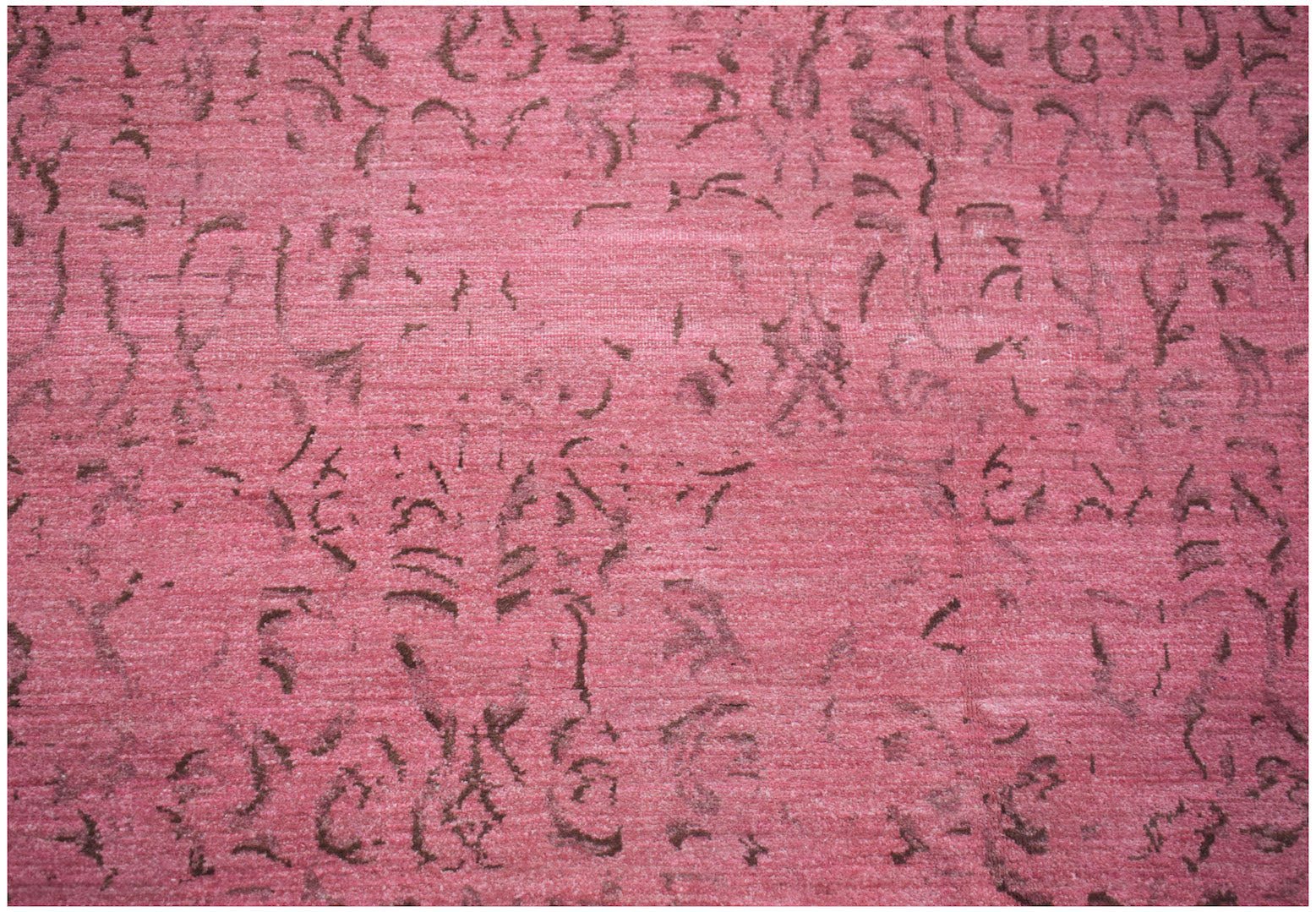 A handmade Afghan Chobi rug featuring a distressed, overdyed pink pattern with dark brown motifs.