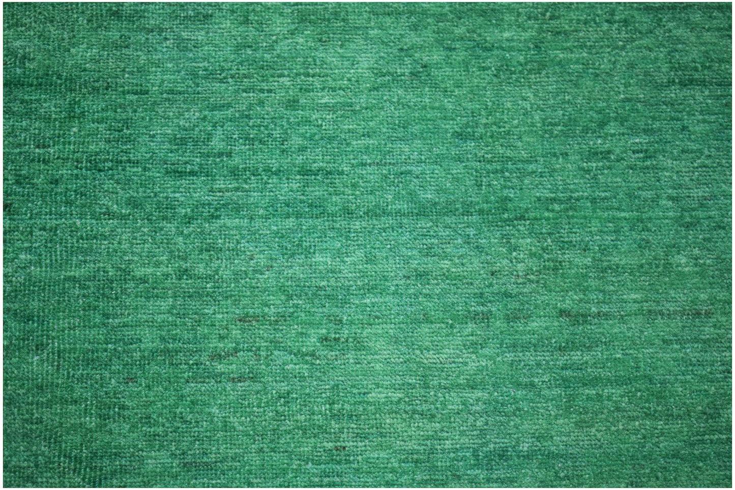 A handmade Afghan Chobi rug featuring a vibrant, overdyed solid green wool texture.