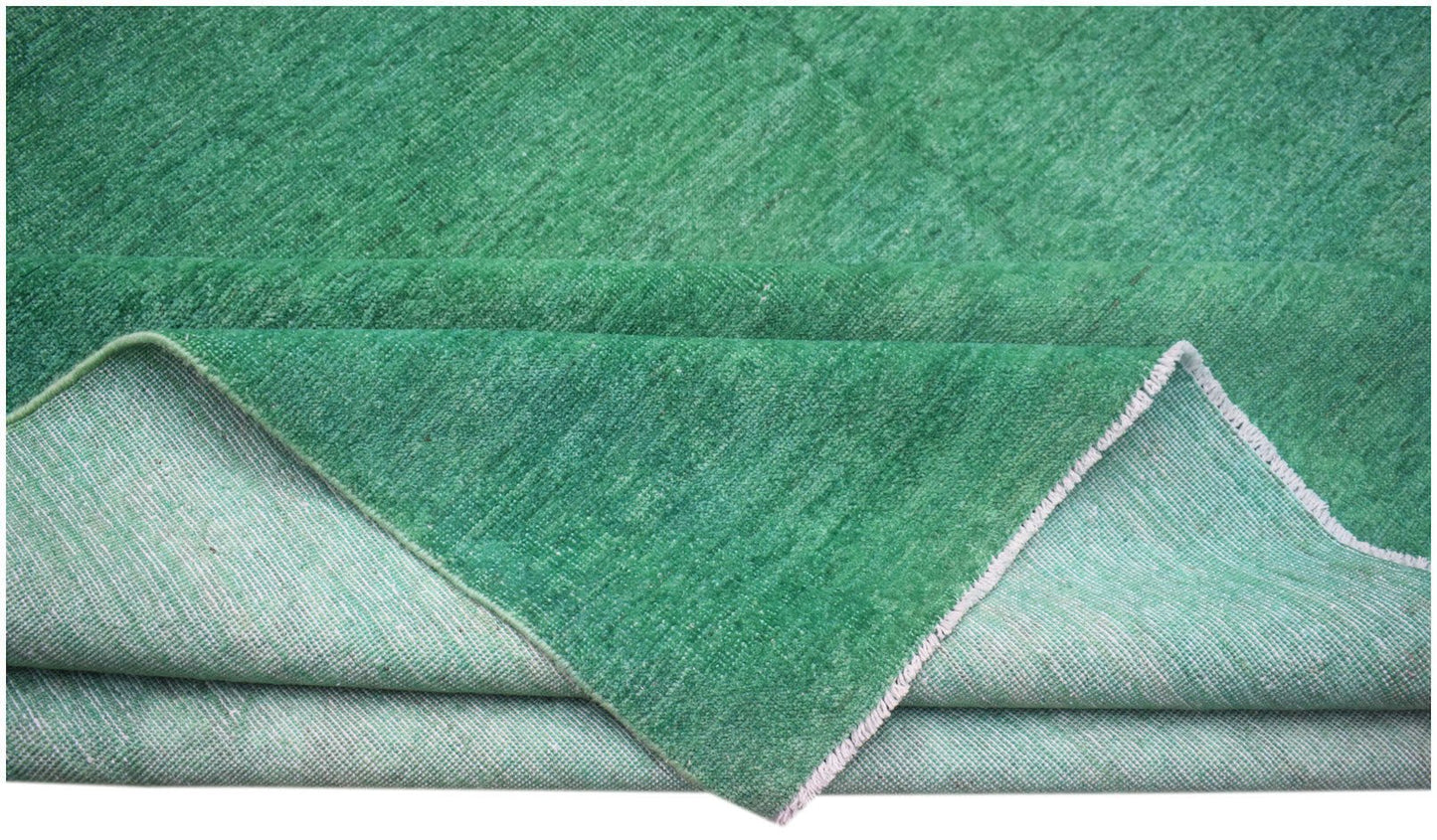 A handwoven Afghan Chobi rug in a solid, overdyed green hue with a visible cotton foundation.