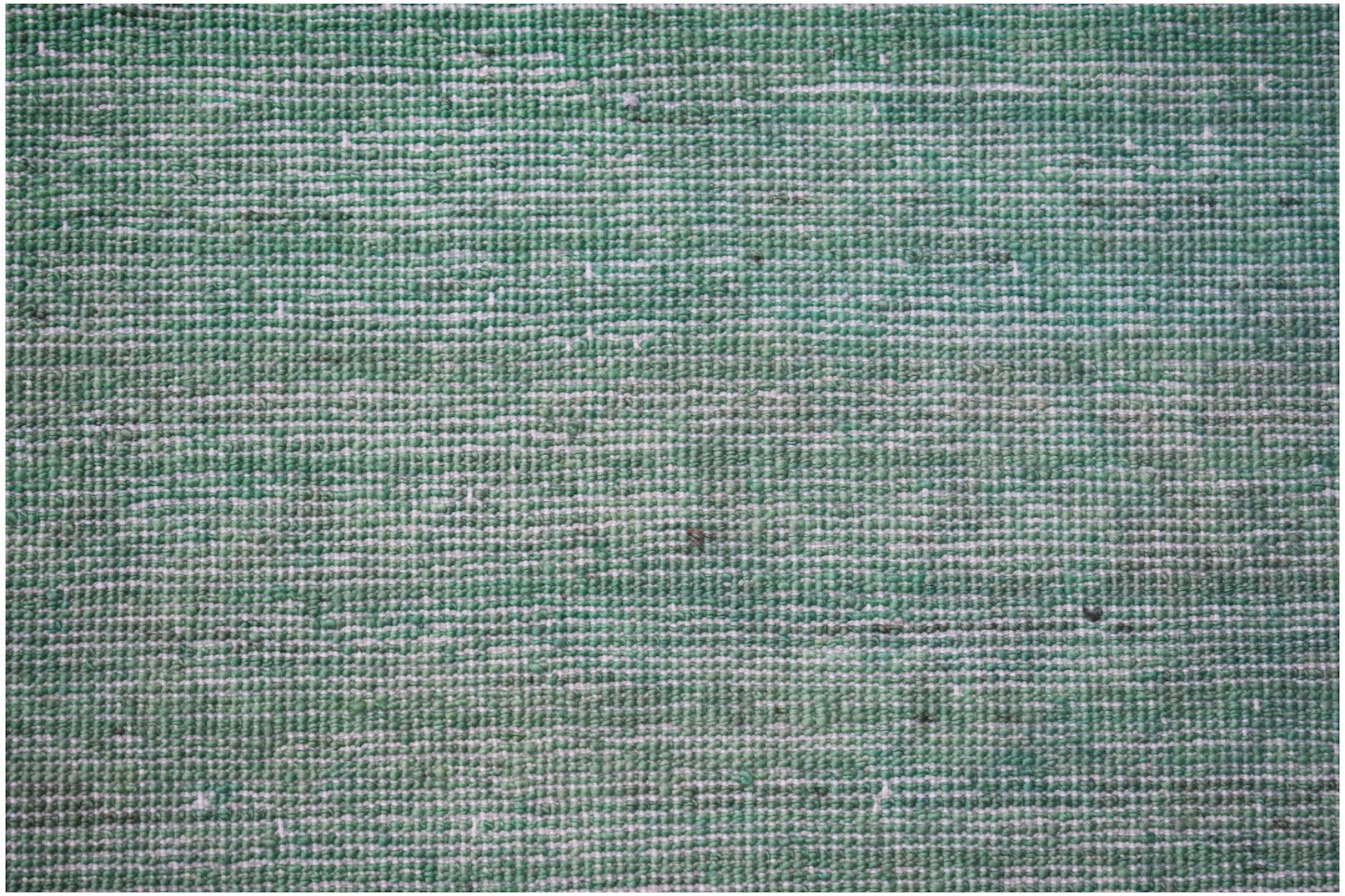A close-up of a handwoven Afghan Chobi rug featuring a textured, overdyed green wool surface.