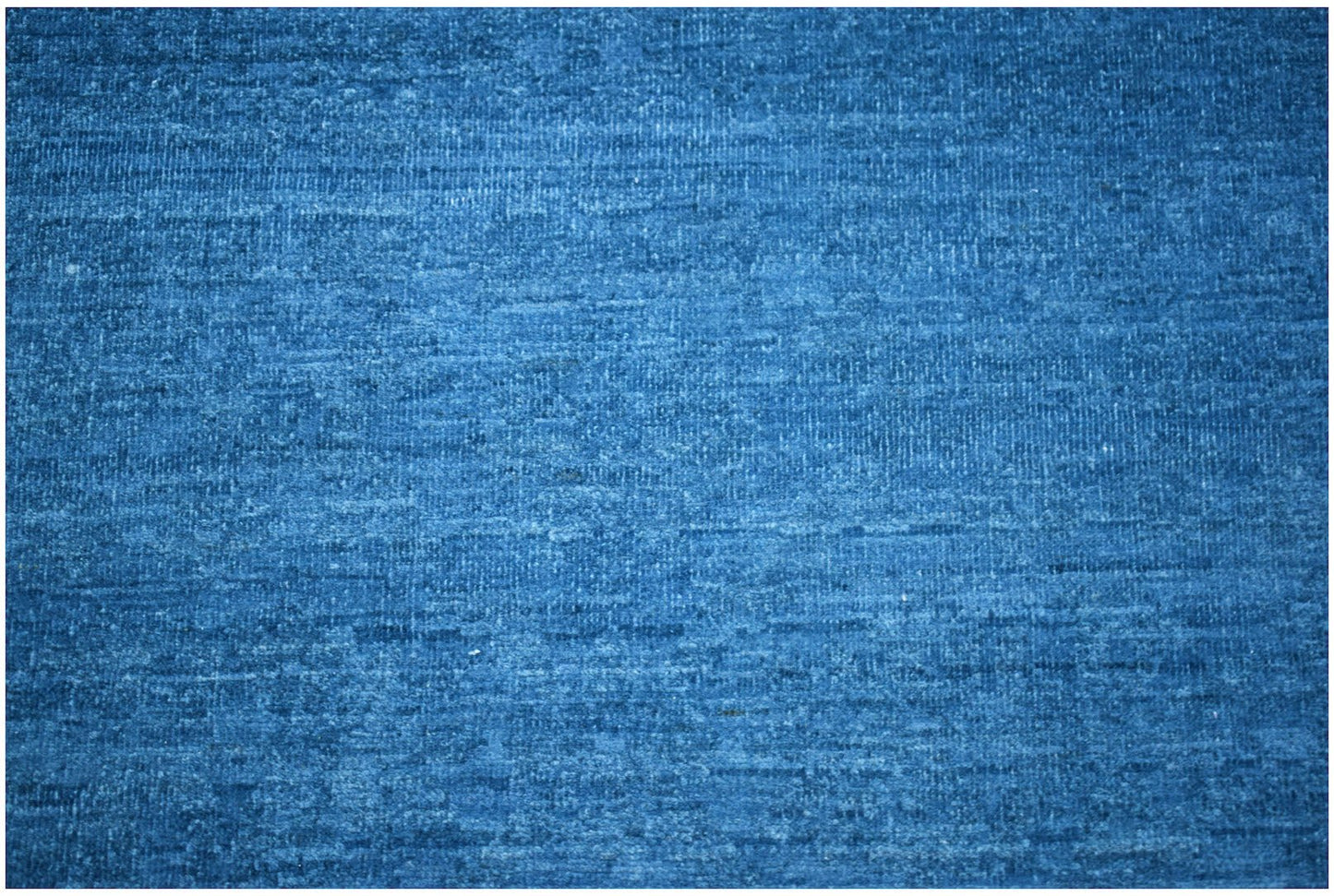 A handwoven Afghan Chobi rug featuring a textured, solid blue wool surface.