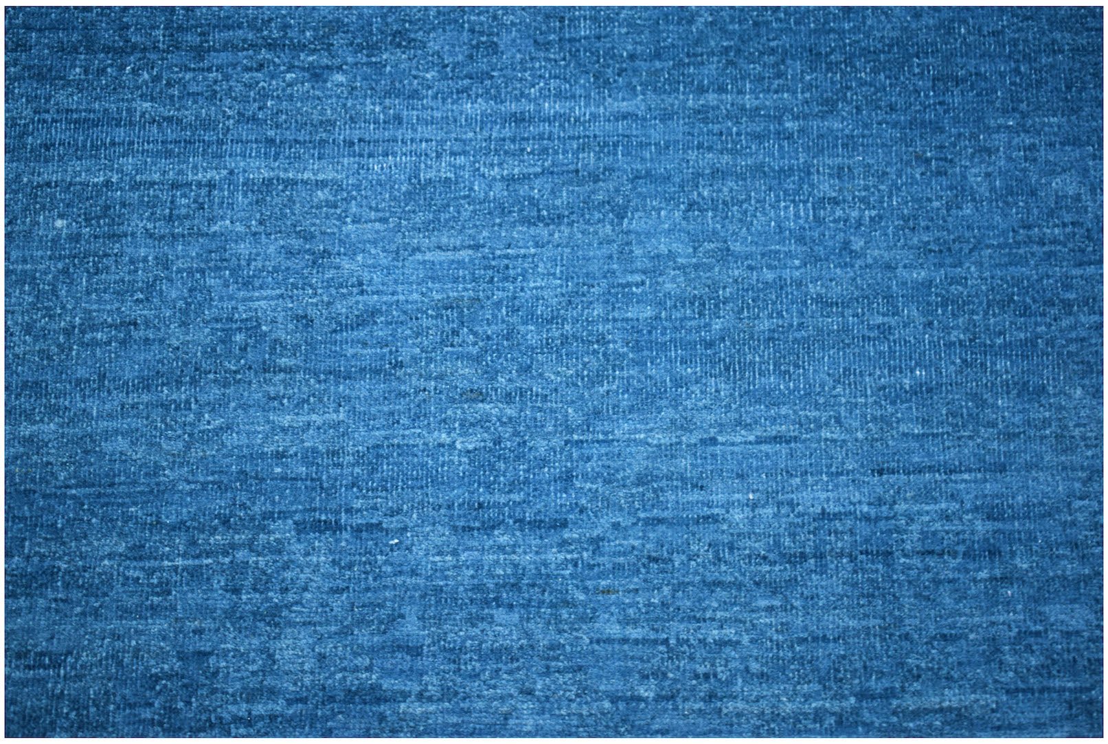 A handwoven Afghan Chobi rug featuring a textured, solid blue wool surface.