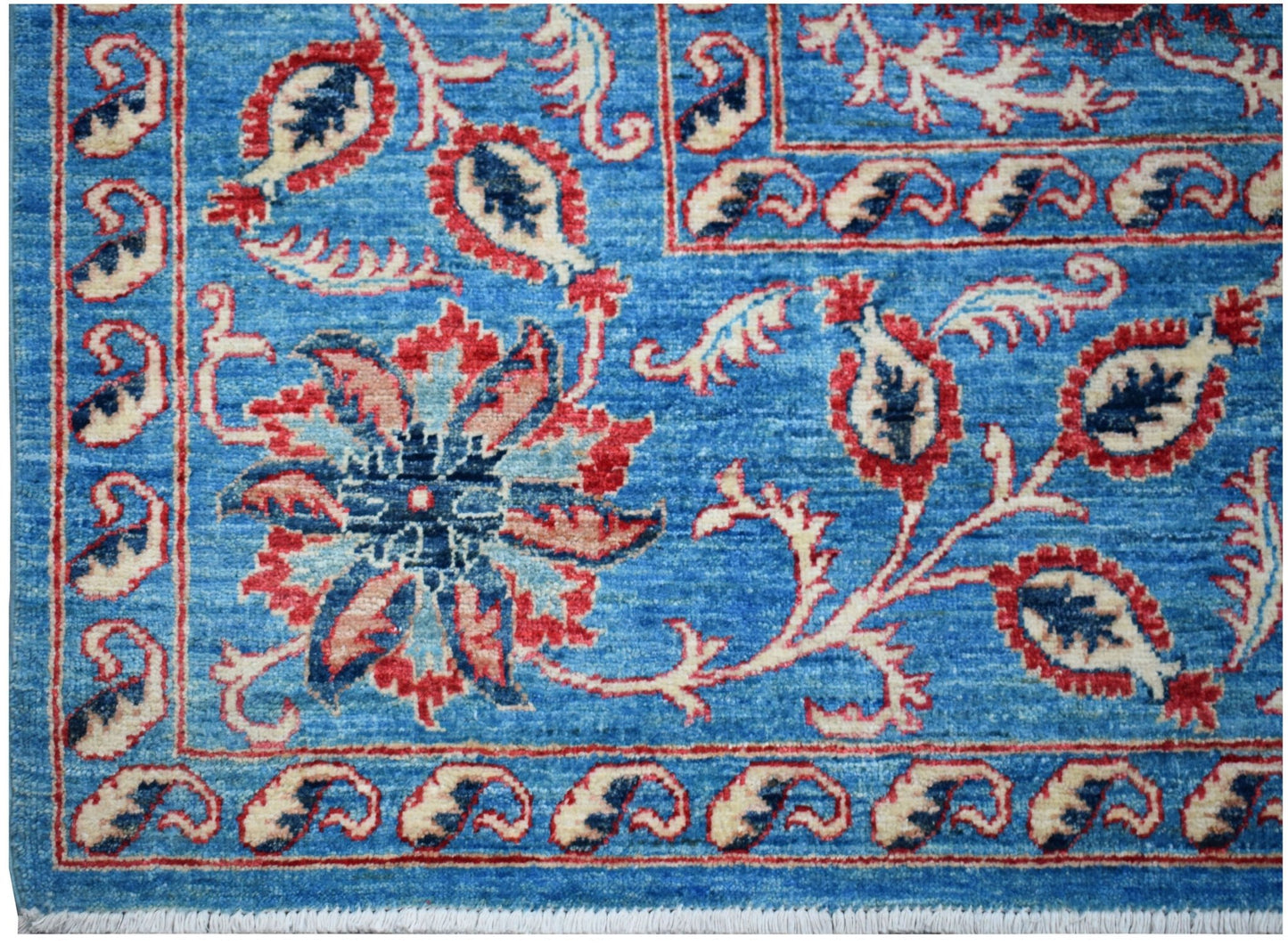 A handmade Afghan Chobi rug featuring a blue field with traditional red and cream floral motifs.