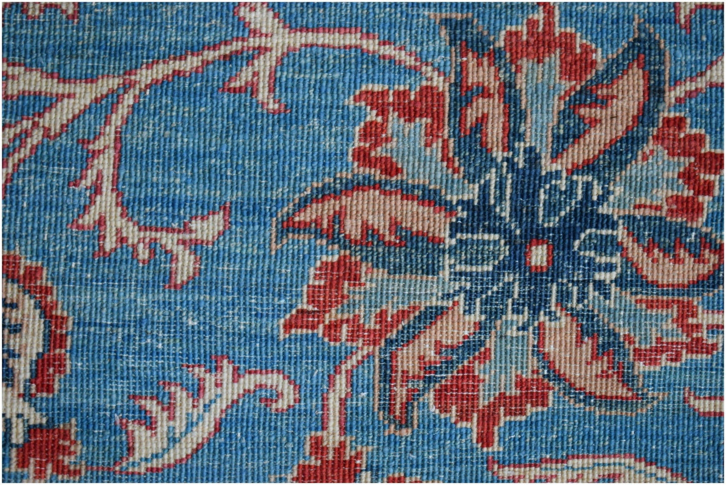 A close-up of a handmade Afghan Chobi rug featuring a traditional blue floral Suzani pattern.