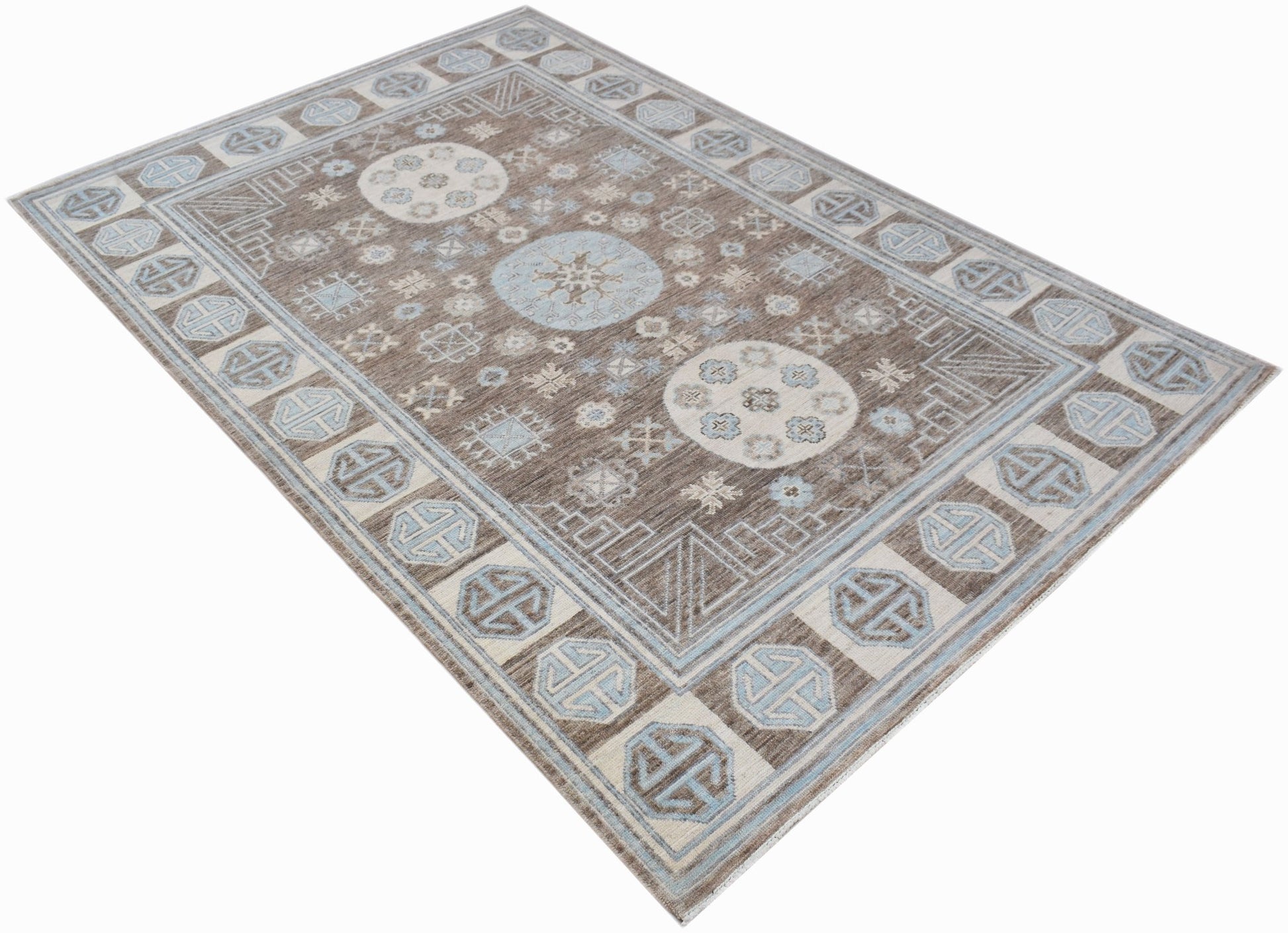 A rectangular transitional Oushak rug featuring a brown field with light blue geometric motifs.