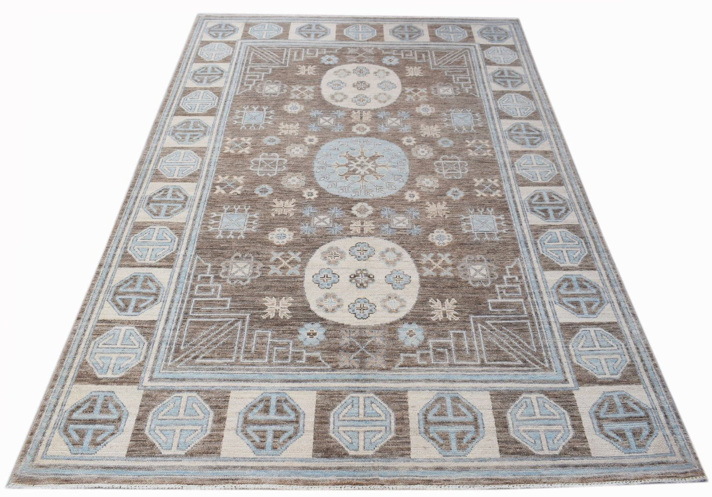 A rectangular transitional Oushak rug featuring a brown field with blue and cream geometric motifs.
