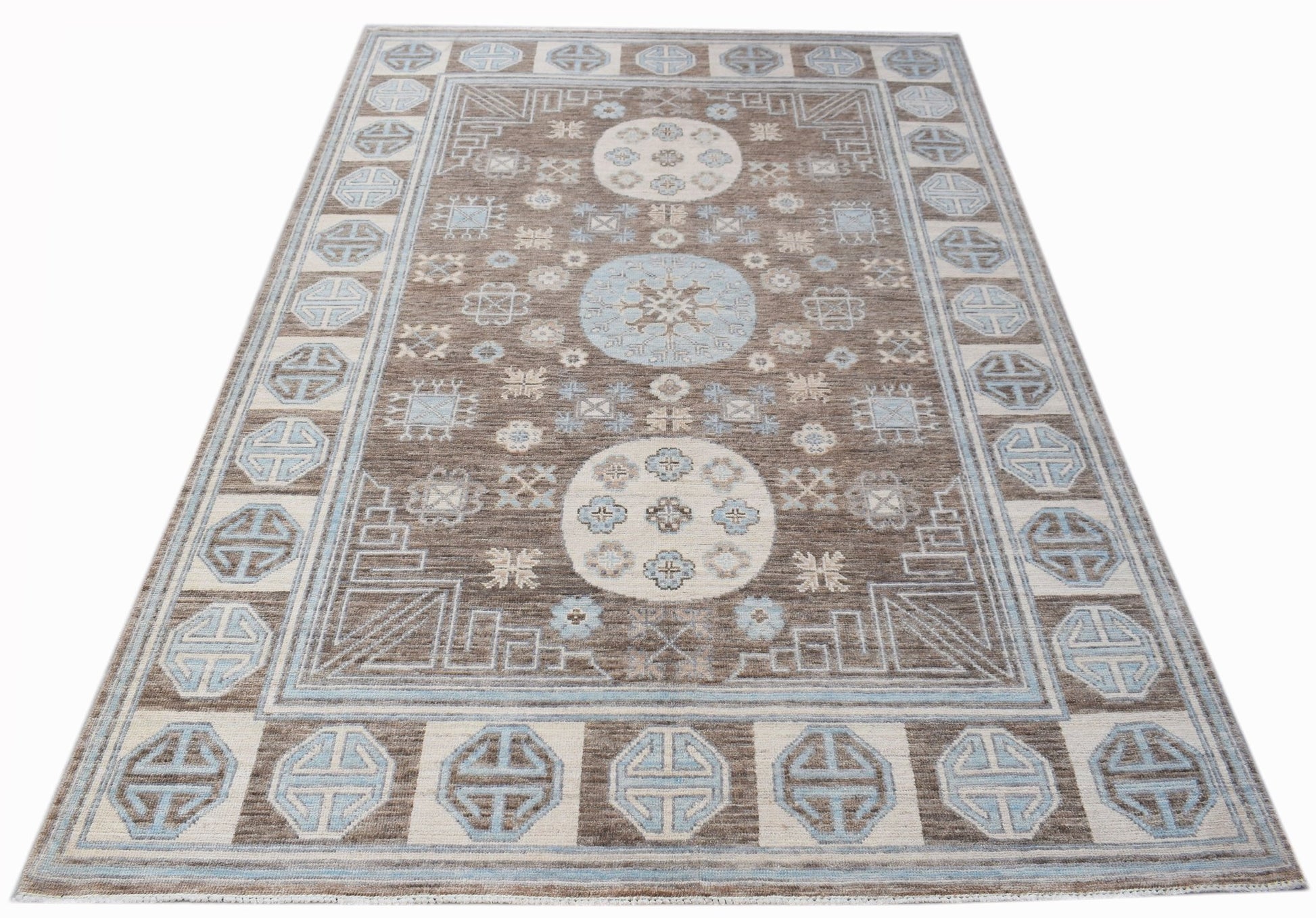A rectangular transitional Oushak rug featuring a brown field with blue and cream geometric motifs.