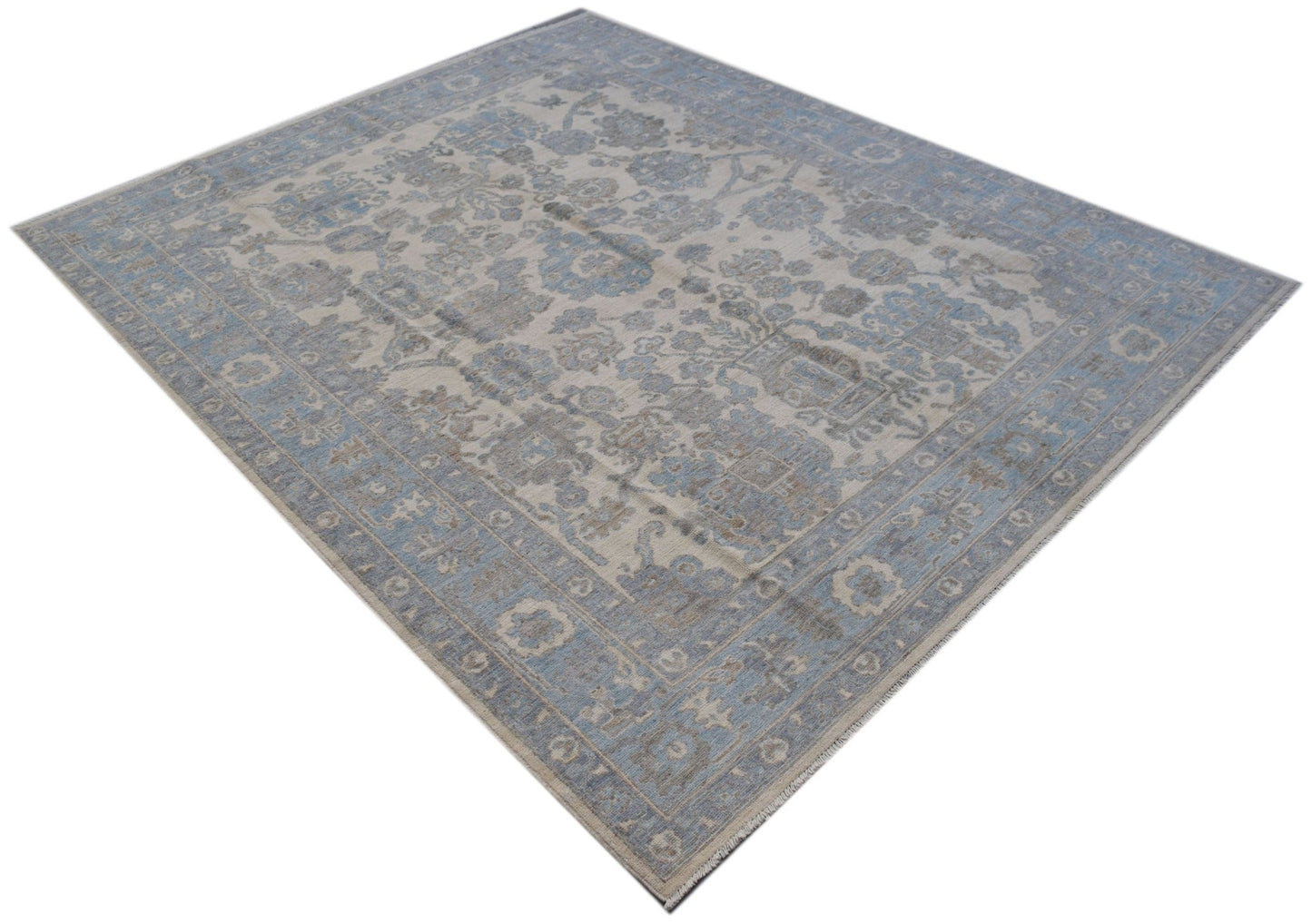 A handmade transitional Oushak rug featuring a soft blue and beige floral pattern.