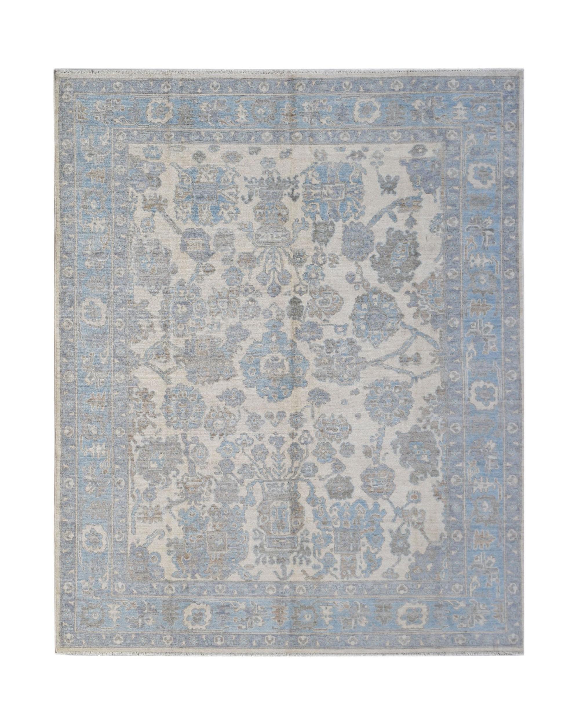 A handmade transitional Oushak rug featuring a soft blue and grey floral pattern on a cream base.