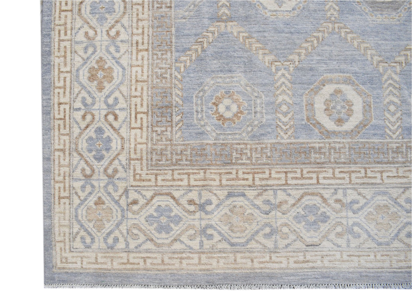 A handmade wool rug featuring a light blue and beige geometric Khotan pattern.