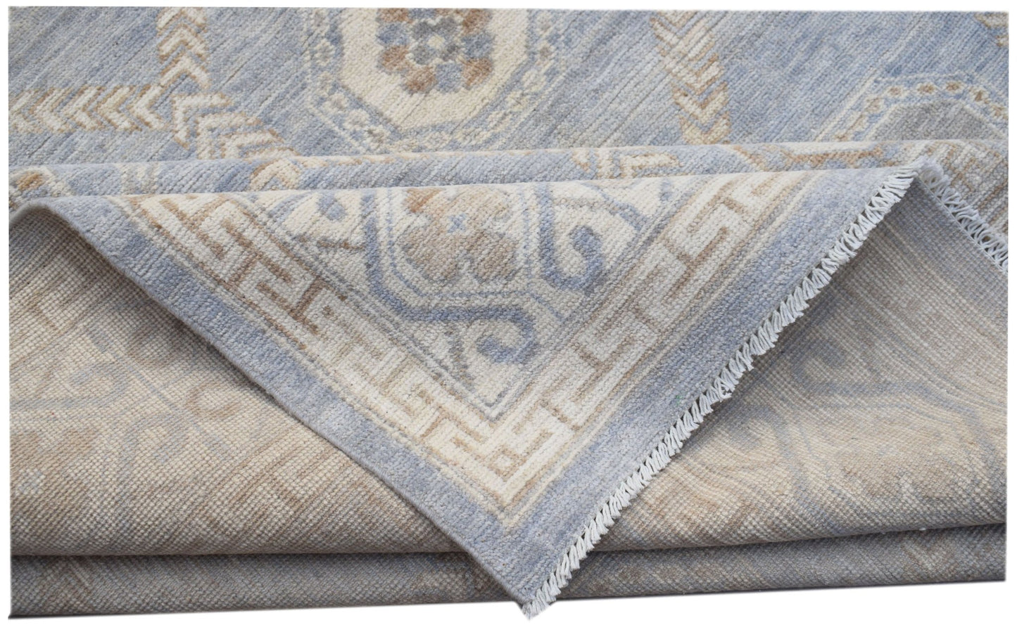 A folded transitional Oushak rug featuring a light blue and beige geometric pattern.