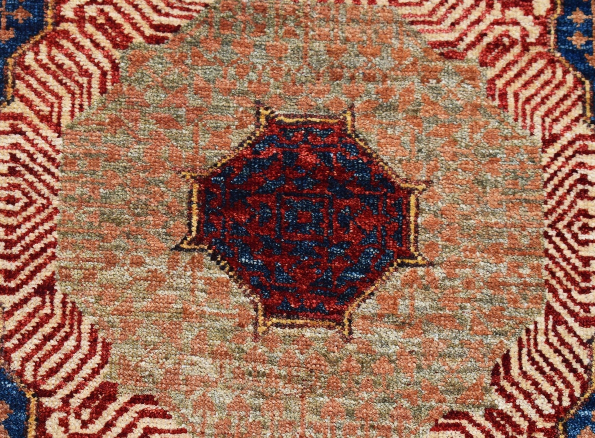 A handwoven Afghan Chobi runner featuring a detailed blue and red Mamluk medallion on a textured tan field.
