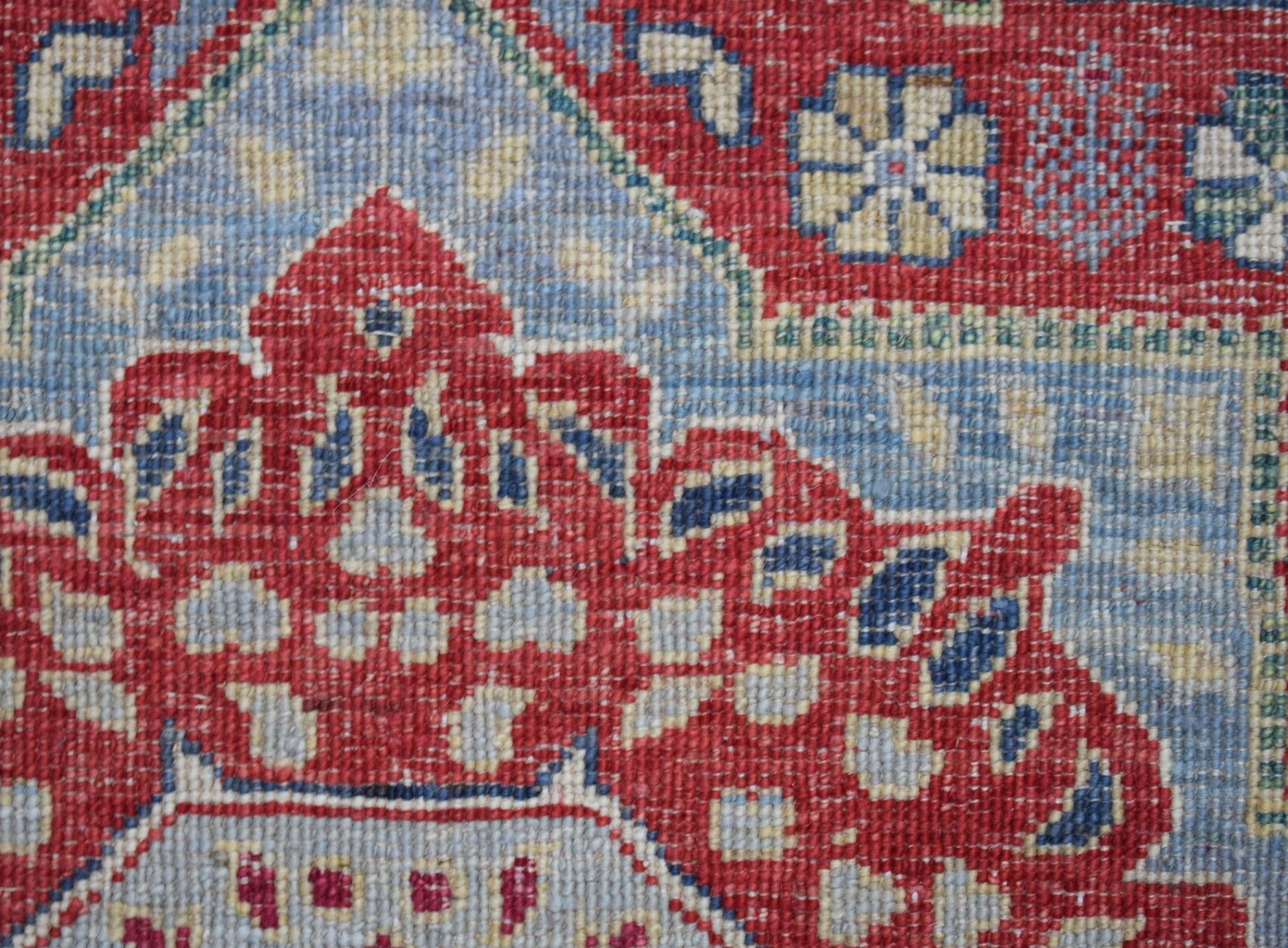 A close-up of a handwoven Afghan Chobi runner featuring a detailed red and blue Mamluk pattern.