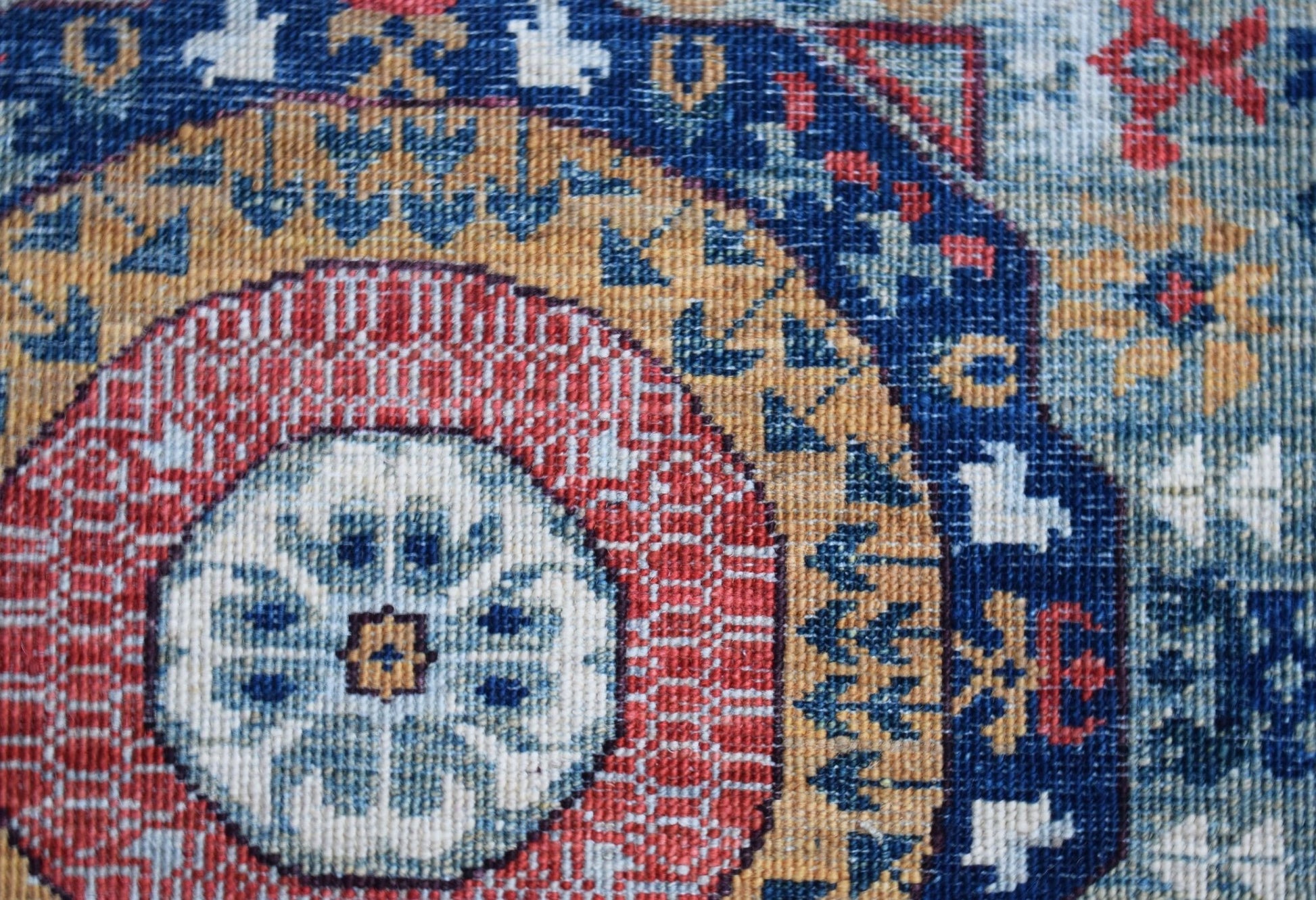 A close-up of a handwoven Afghan Chobi runner featuring a detailed red and blue Mamluk medallion.