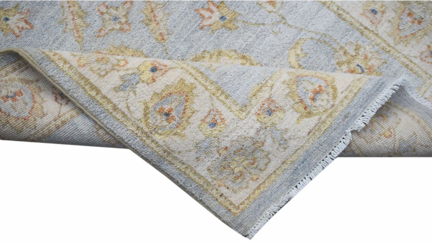 A handwoven Afghan Chobi rug featuring a light blue field with traditional floral patterns.