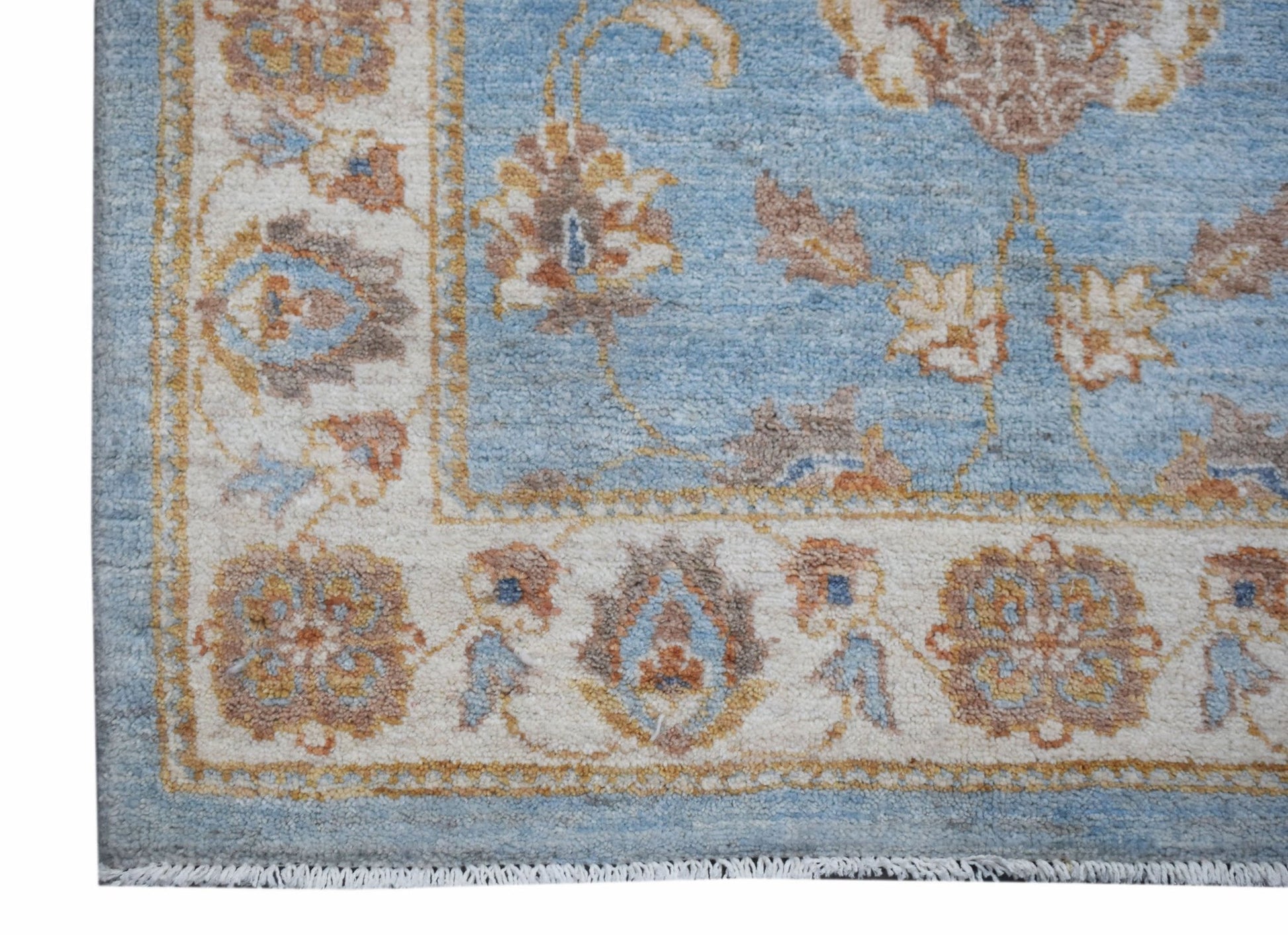 A handmade Afghan Chobi rug featuring a light blue field with floral patterns and a cream border.