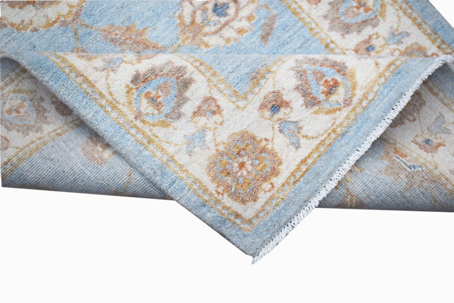 A handwoven Afghan Chobi rug featuring a light blue and cream floral pattern with a fringed edge.