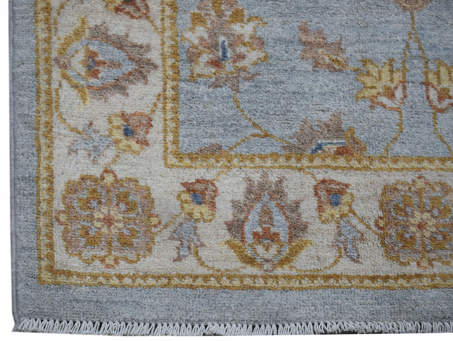 A handwoven Afghan Chobi rug featuring a traditional floral pattern in soft blue and earthy tones.
