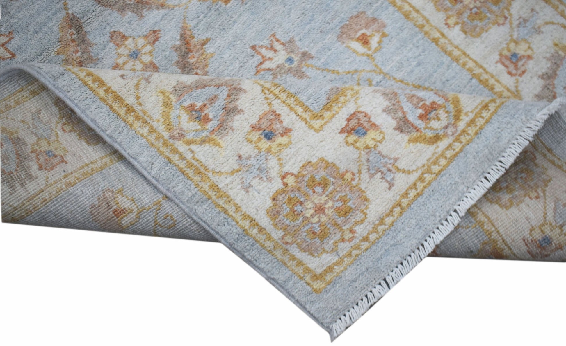 A handwoven Afghan Chobi rug featuring a traditional floral pattern in soft blue and beige tones.