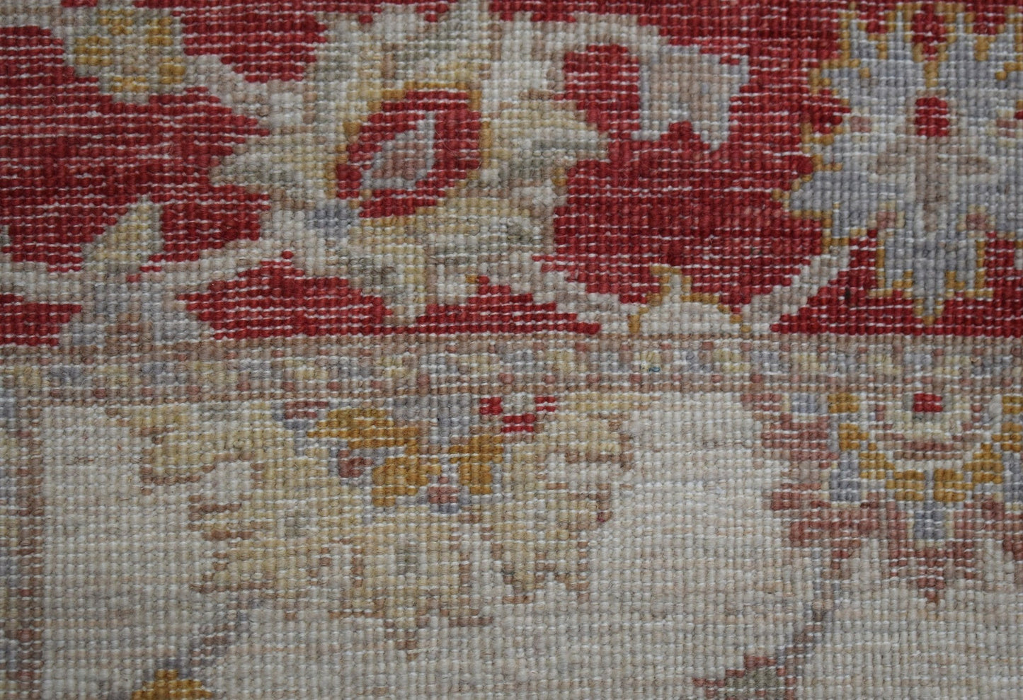 A close-up view of a handwoven Afghan Chobi rug featuring traditional floral patterns in red and tan.