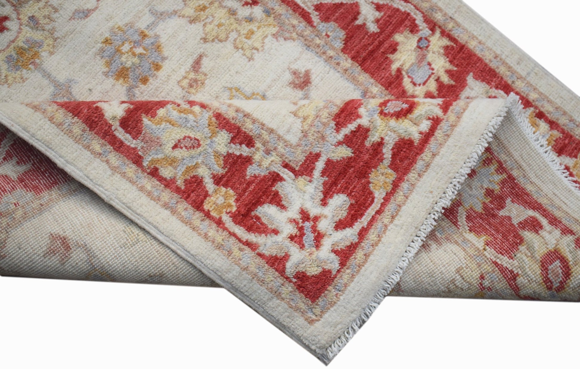 A handmade Afghan Chobi rug featuring a traditional floral pattern in red, cream, and soft tones.