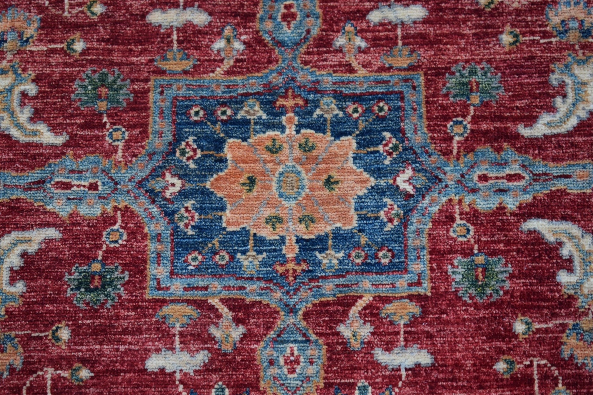 A handmade Afghan Chobi rug featuring a central floral medallion on a deep red background.