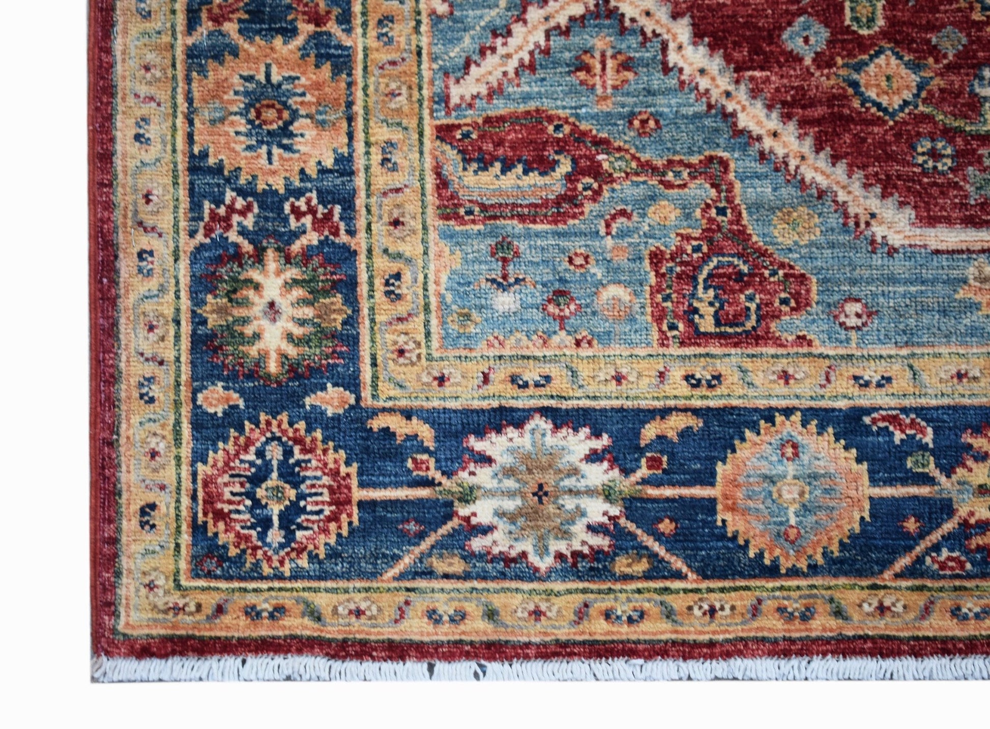 A corner view of a handwoven Afghan Chobi rug featuring intricate floral patterns in blue and red.