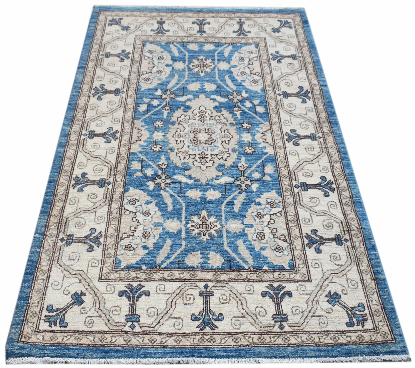 A rectangular Afghan Chobi rug featuring a blue central medallion and floral patterns on cream.