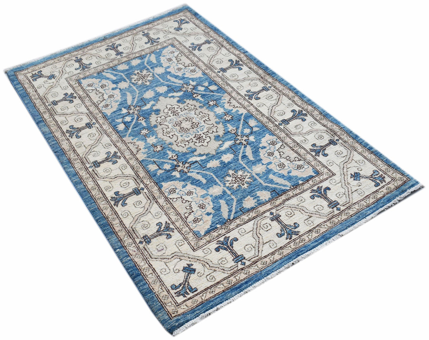 A rectangular Afghan Chobi rug featuring a blue field with intricate cream floral patterns.